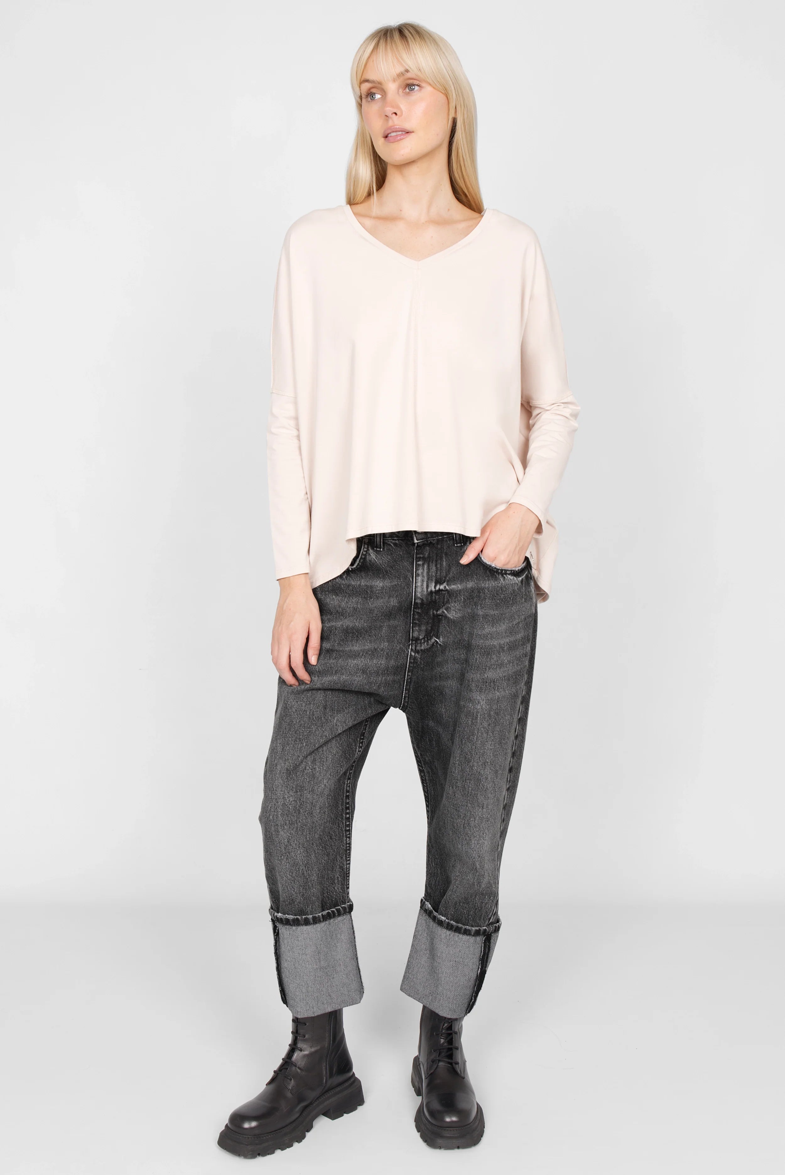 Frau trägt rosa TIDA Blusenshirt Langarm mit V-Ausschnitt und weiten Kastenform kombiniert mit schwarzen Jeans und Stiefeln