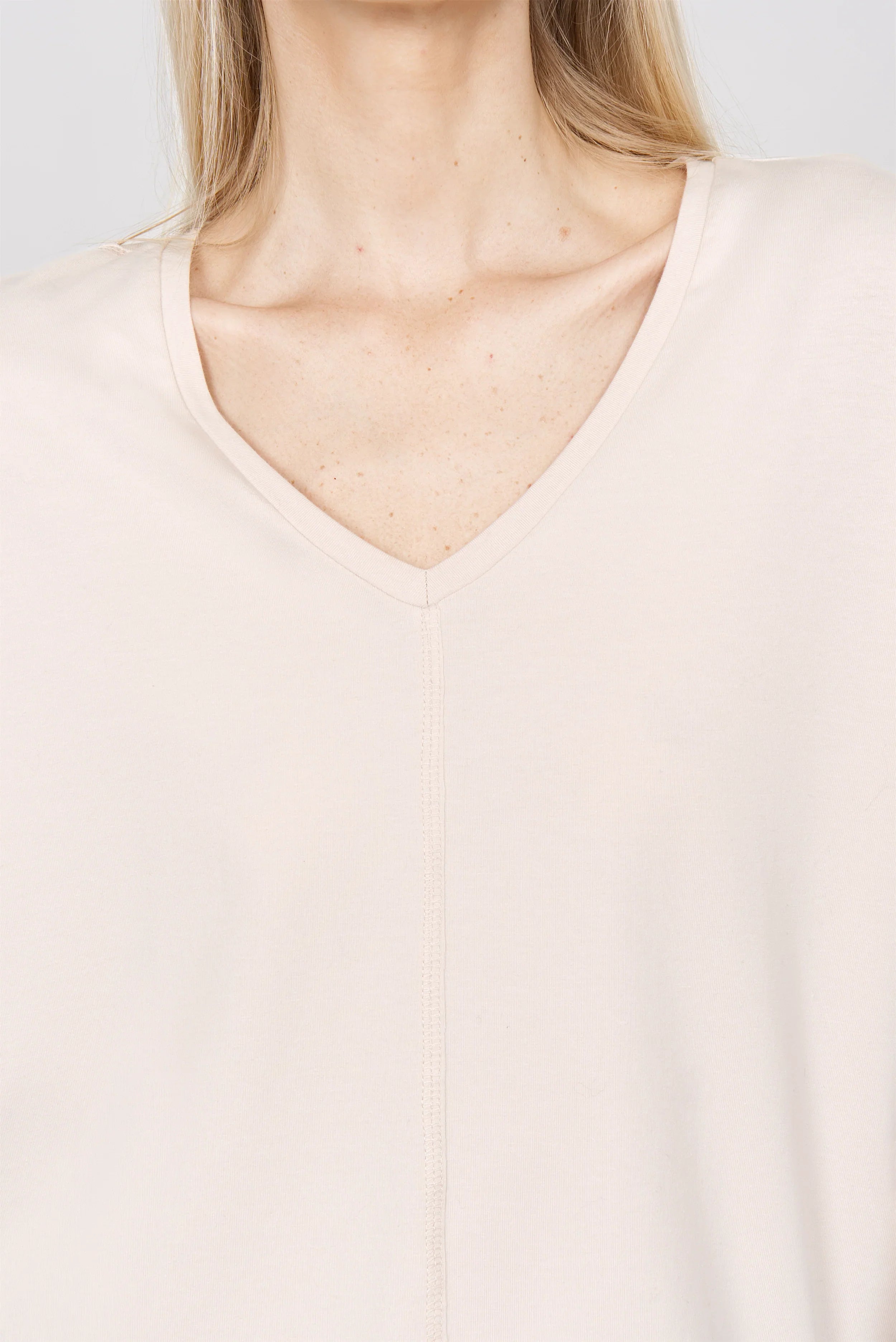 Nahaufnahme eines beigen TIDA Blusenshirt Langarm mit V-Ausschnitt und lockerem, kastigem Schnitt aus hochwertiger Baumwolle