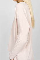 Side view of a woman wearing a TIDA Blusenshirt Langarm in soft pink with relaxed, boxy fit and long sleeves