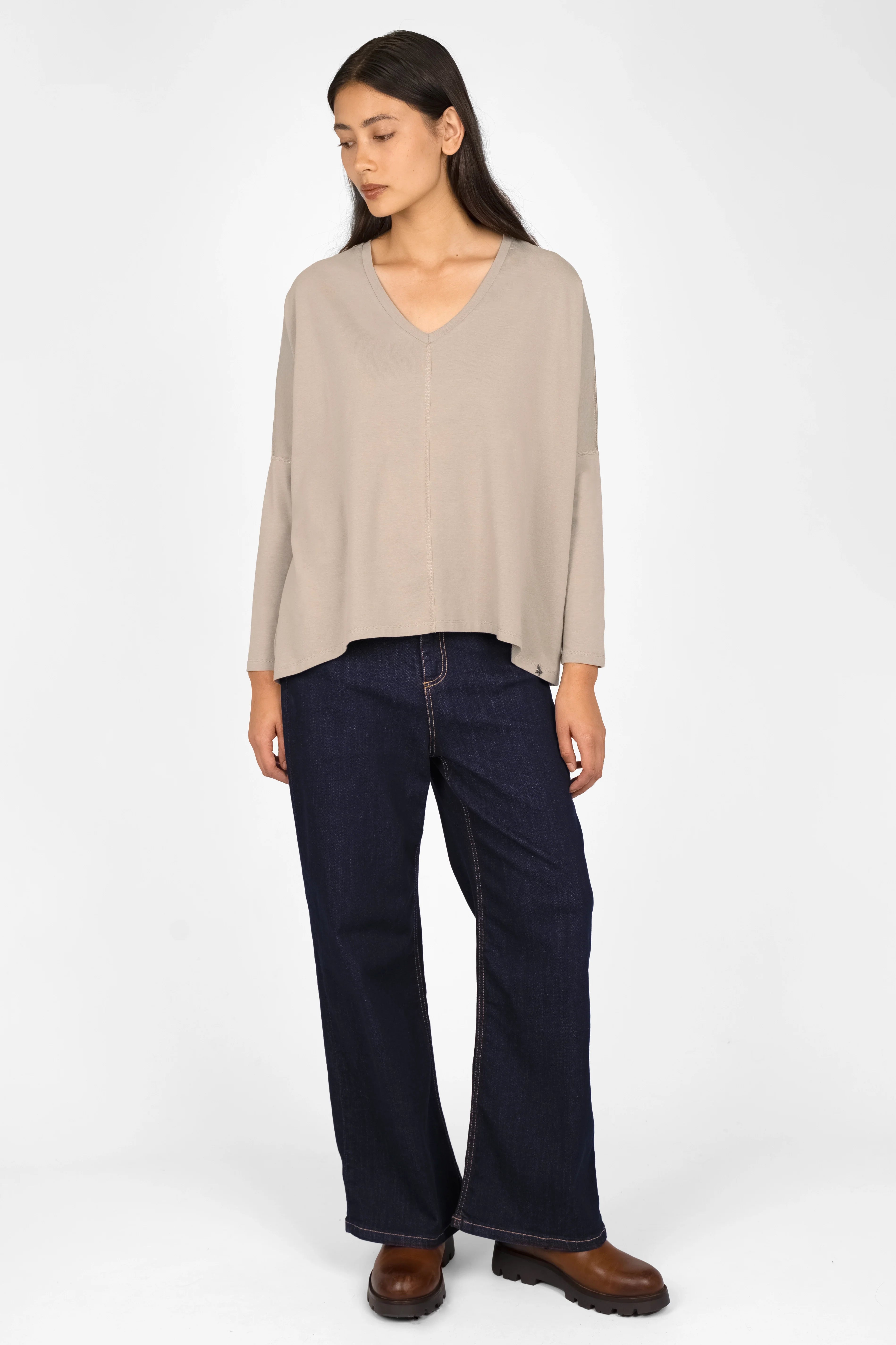 Woman wearing beige TIDA Blusenshirt Langarm with V-neck, relaxed fit, and long sleeves paired with dark wide-leg jeans and brown shoes