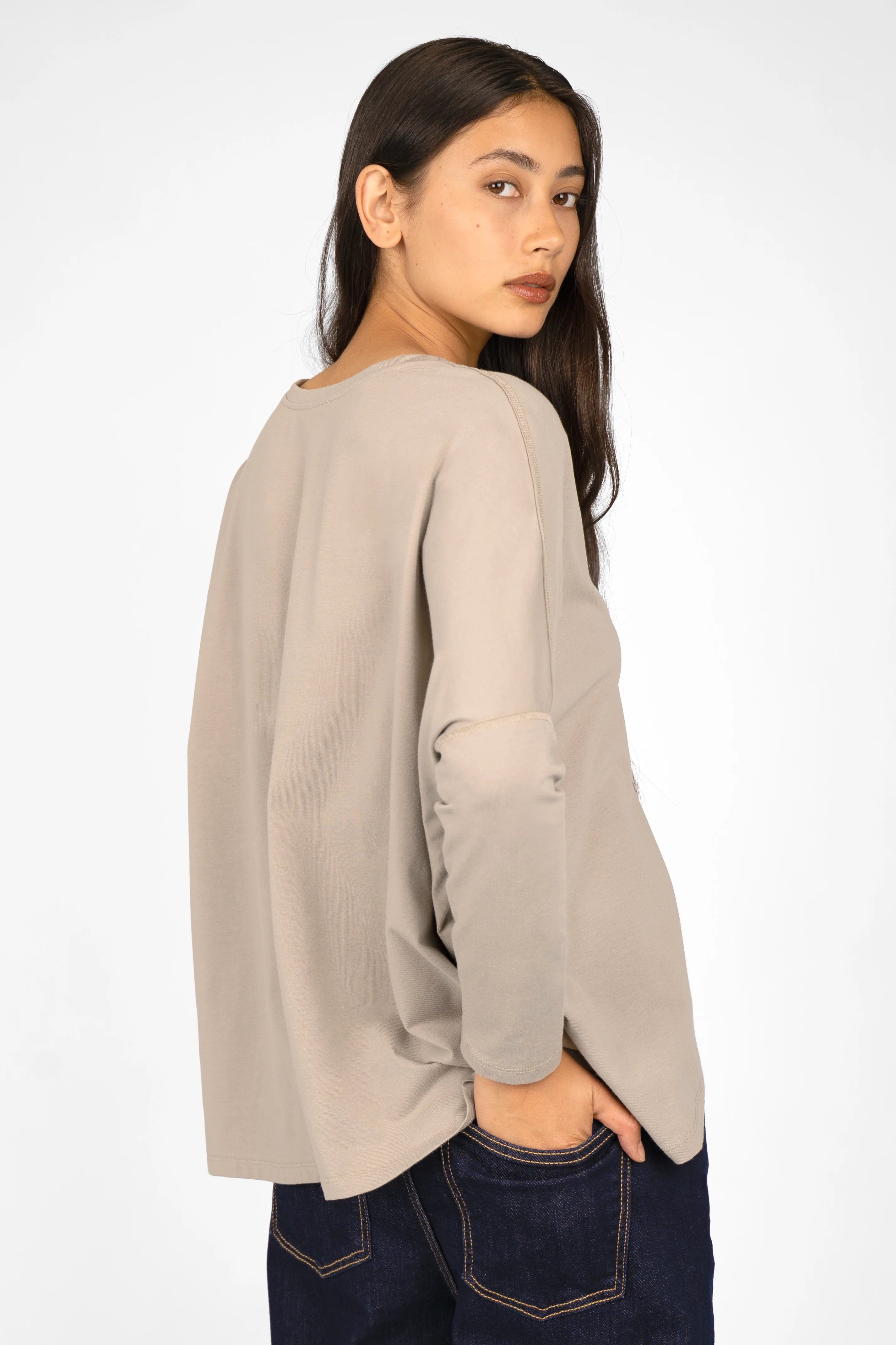 Woman wearing beige TIDA Blusenshirt Langarm with relaxed fit, V-neck, and longer back hem.