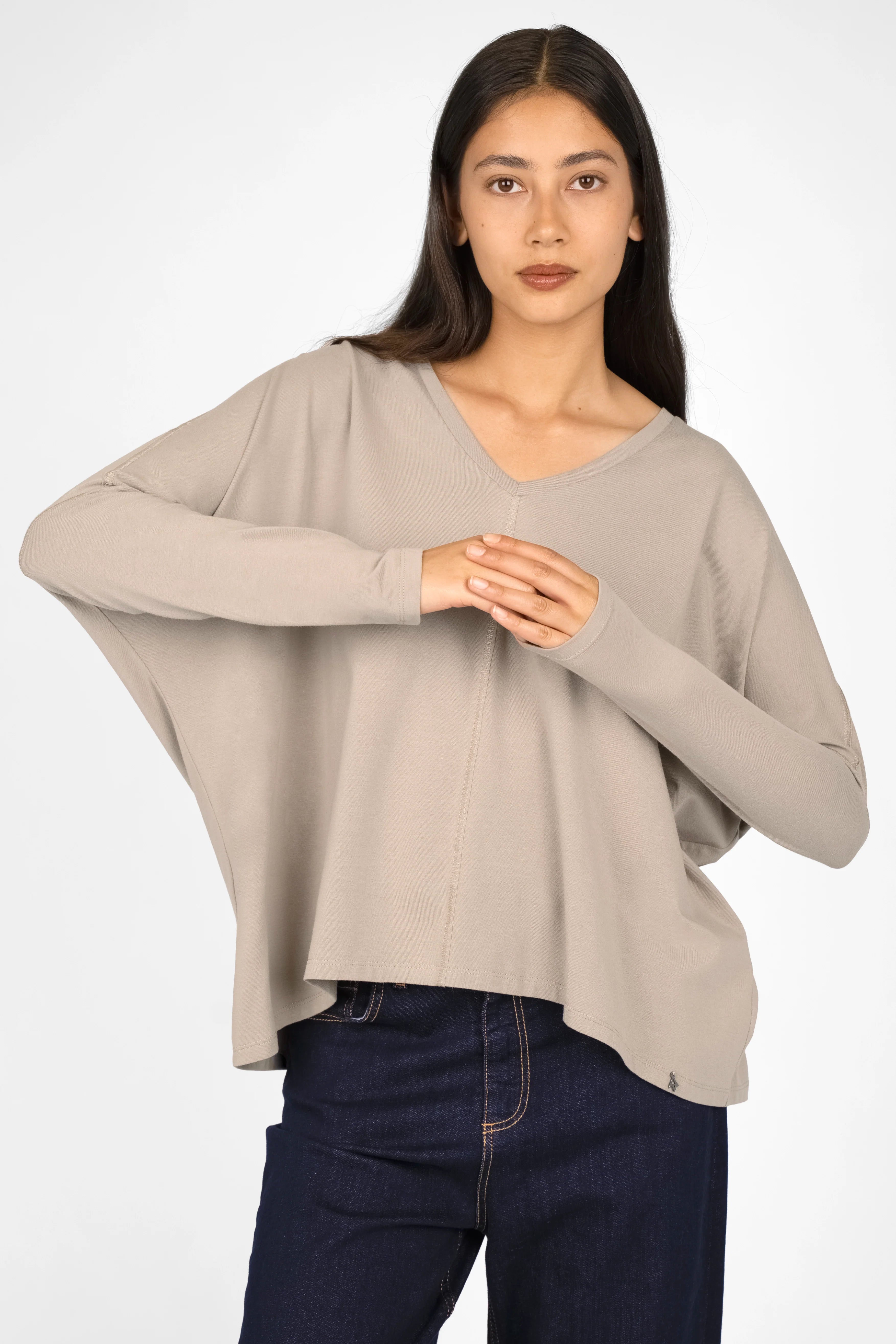 Woman wearing TIDA Blusenshirt Langarm loose long-sleeve V-neck shirt in beige with relaxed boxy fit and rounded hem