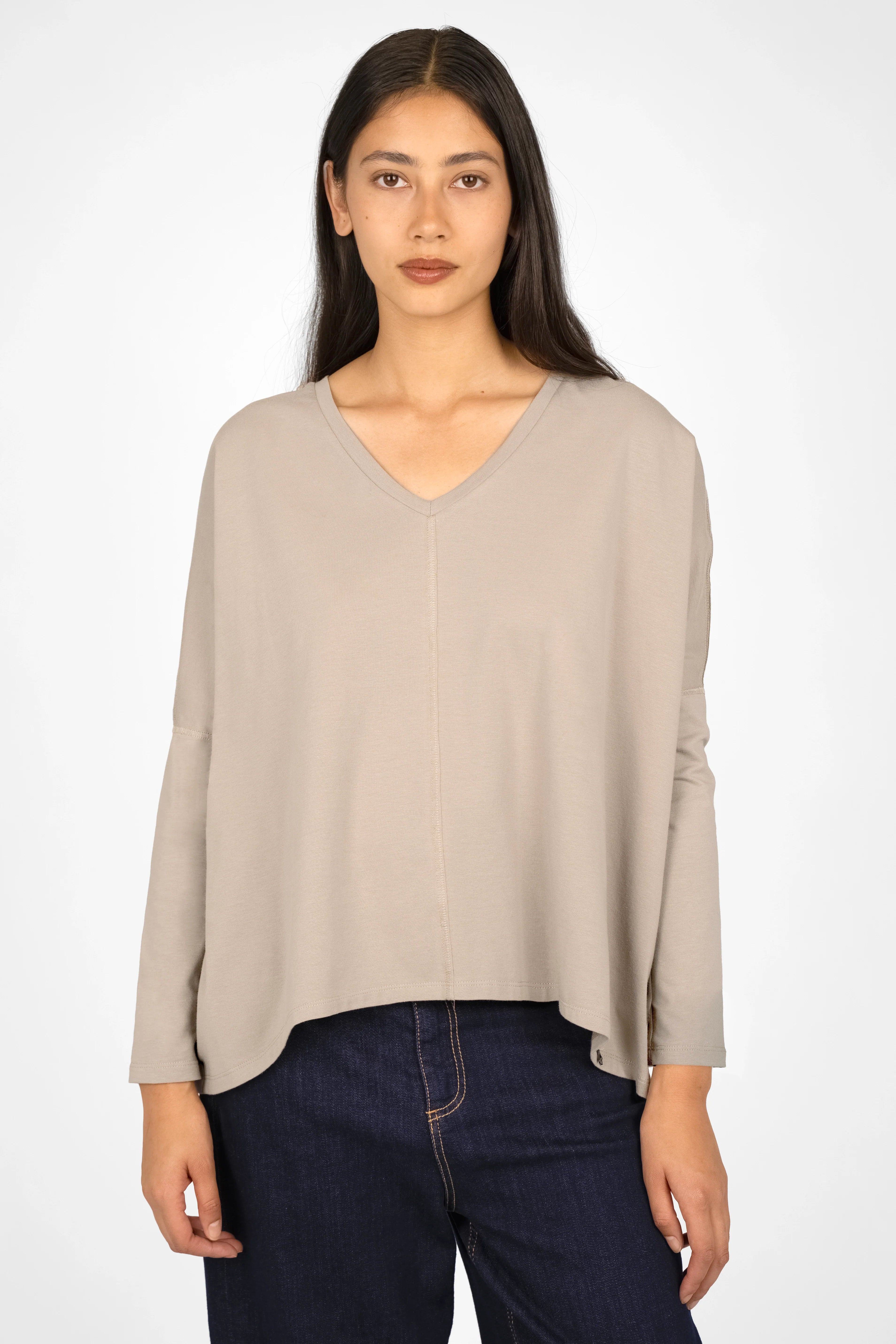 Woman wearing a beige TIDA Blusenshirt Langarm with V-neck, relaxed fit, and long sleeves paired with dark jeans