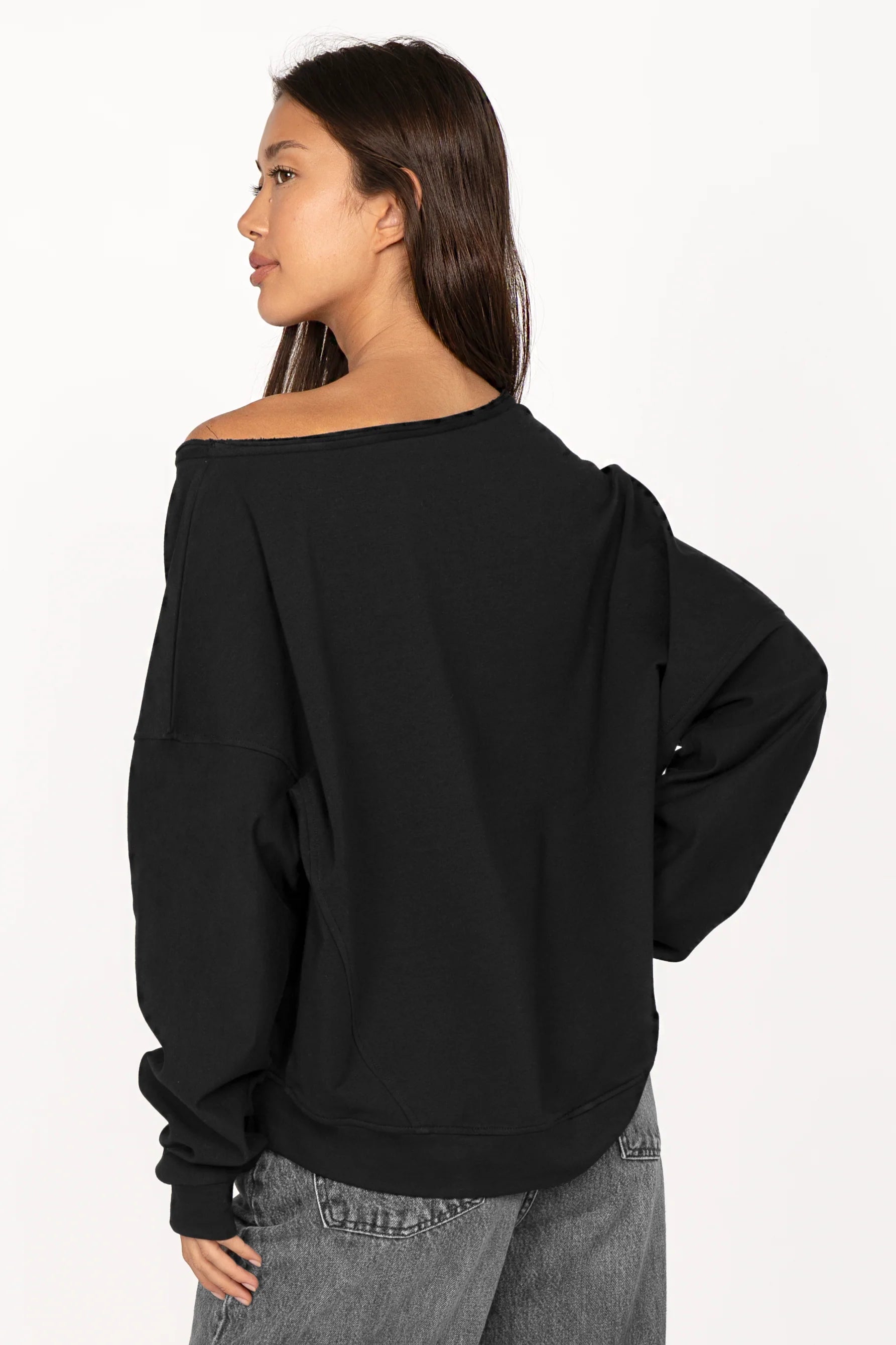 Black one shoulder sweater with relaxed fit, wide neckline, cuffed sleeves, and longer back hem.