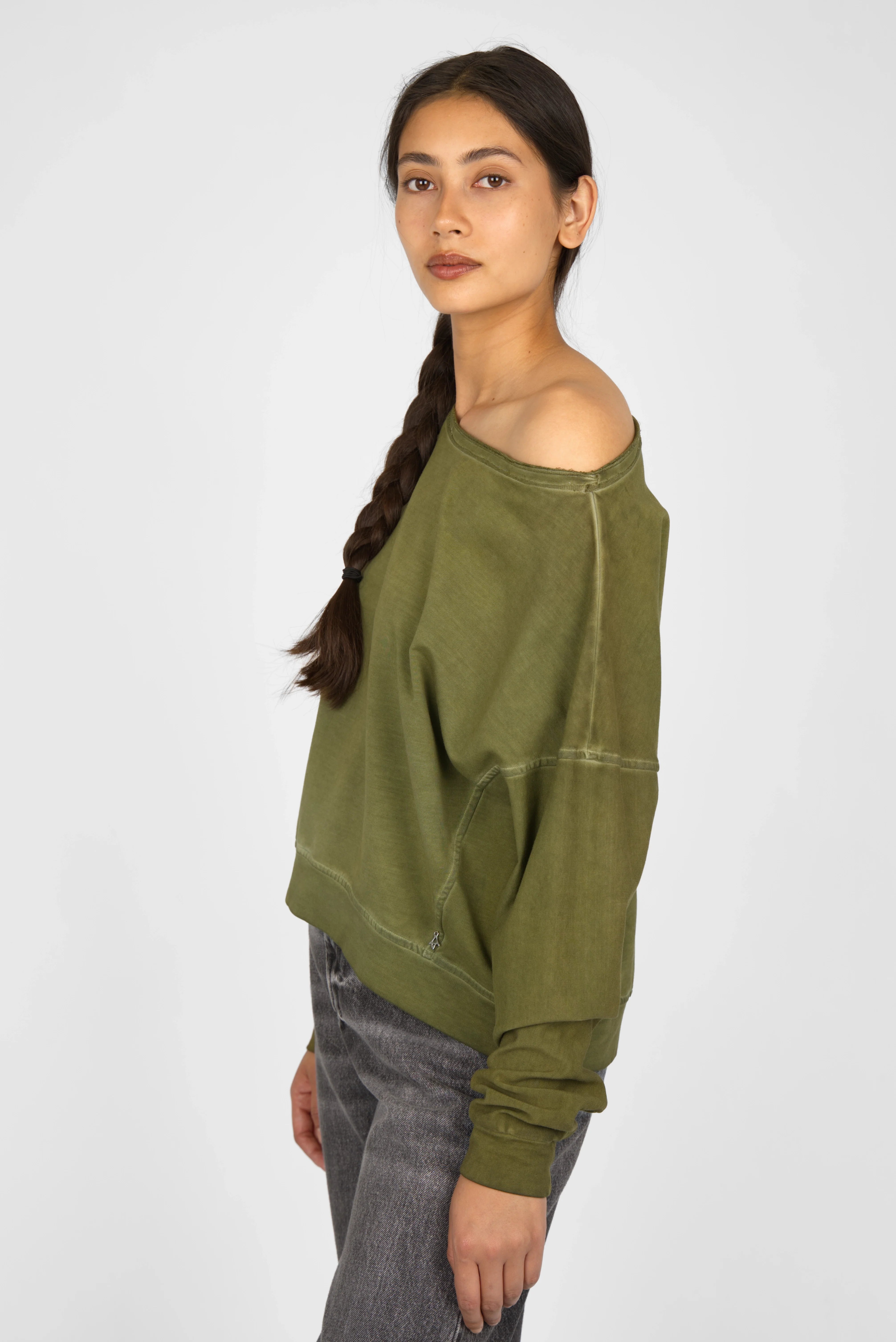 Woman wearing olive green TIMAJ Revive One Shoulder Sweater with loose fit and wide neckline exposing one shoulder