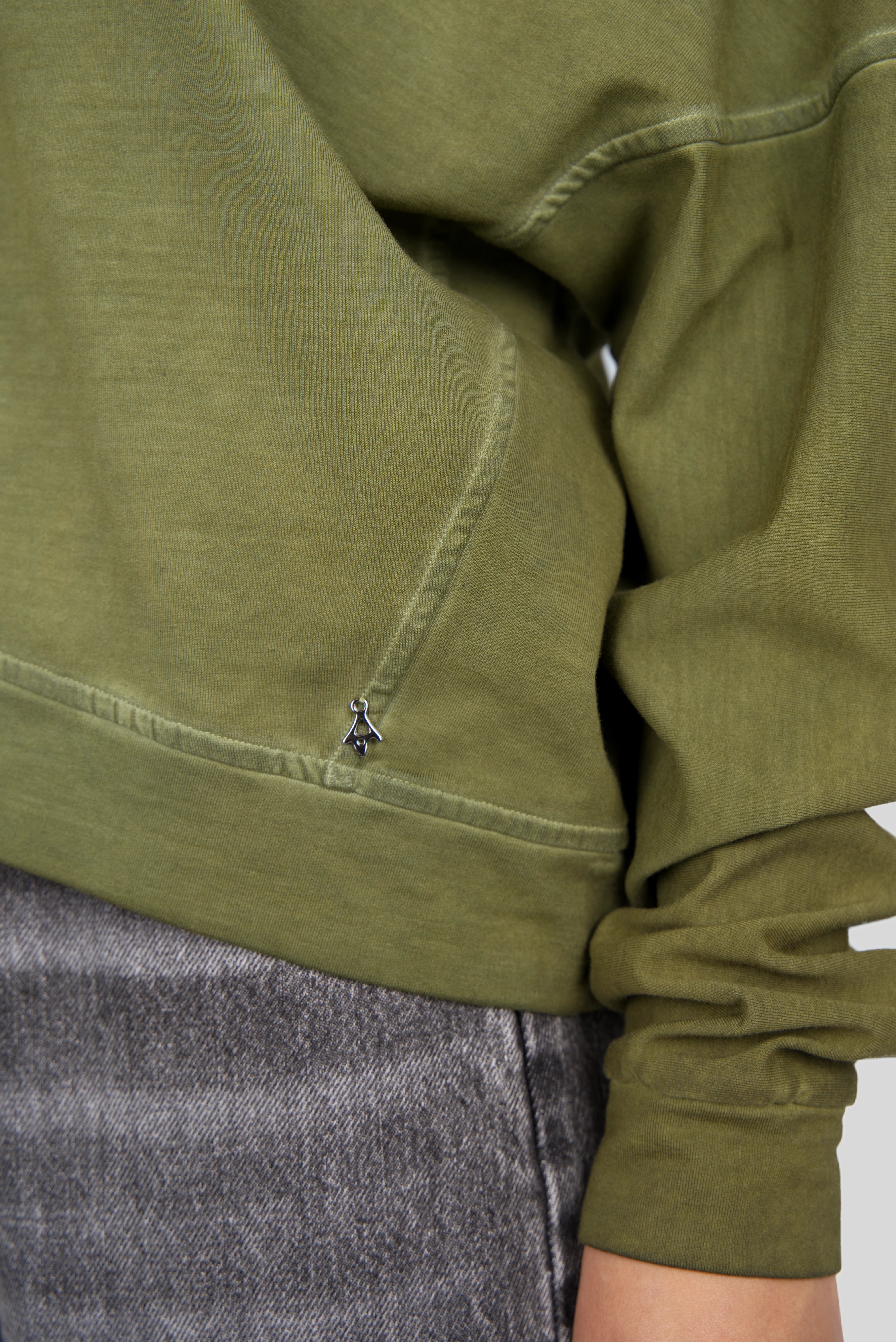 Close-up of olive green TIMAJ Revive One Shoulder Sweater with ribbed cuff and hem, featuring a relaxed fit and raw edge detailing.