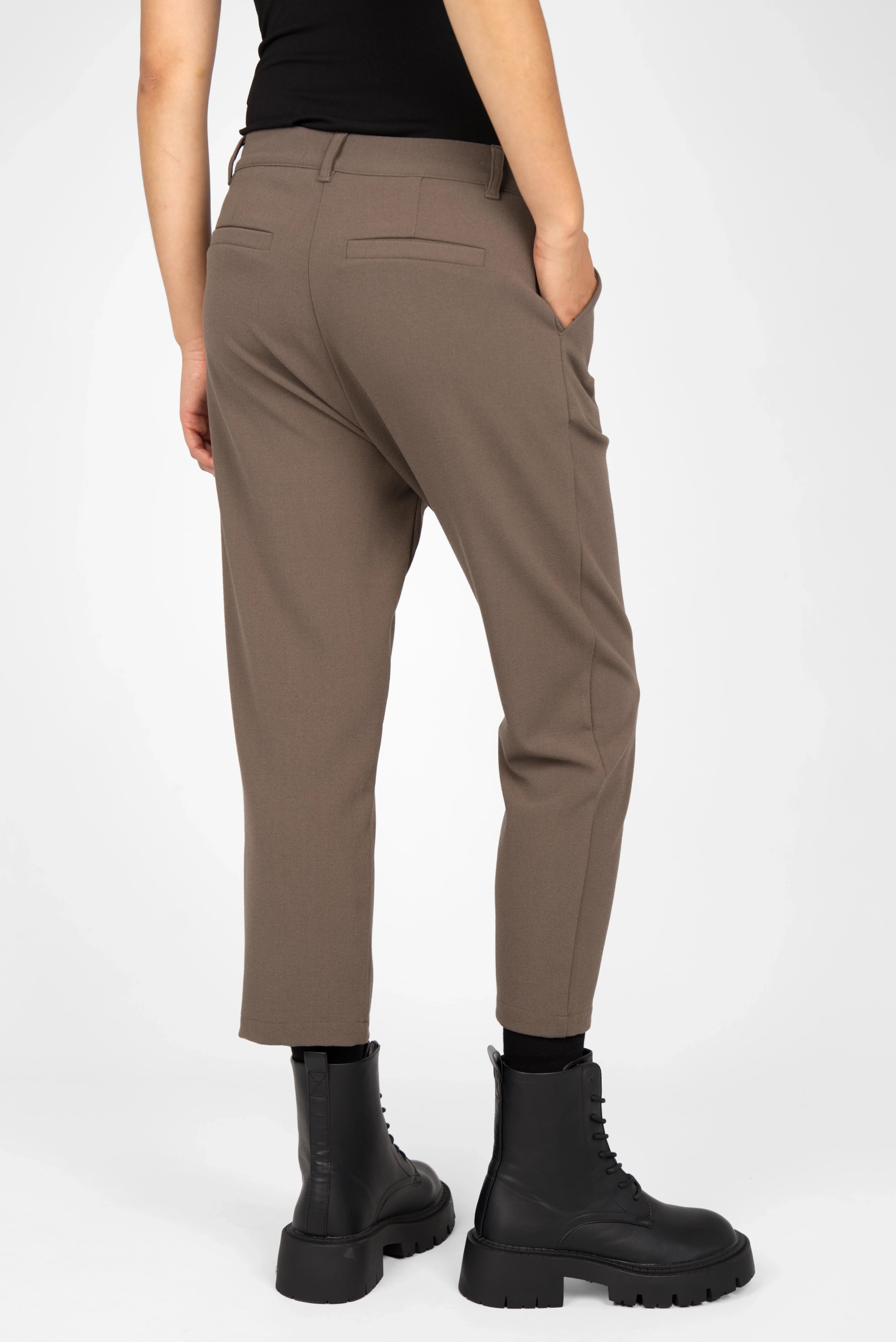 Back view of a person wearing brown TINKE Hose Cropped fit pants with a slightly loose hip fit, cropped length, and black ankle boots