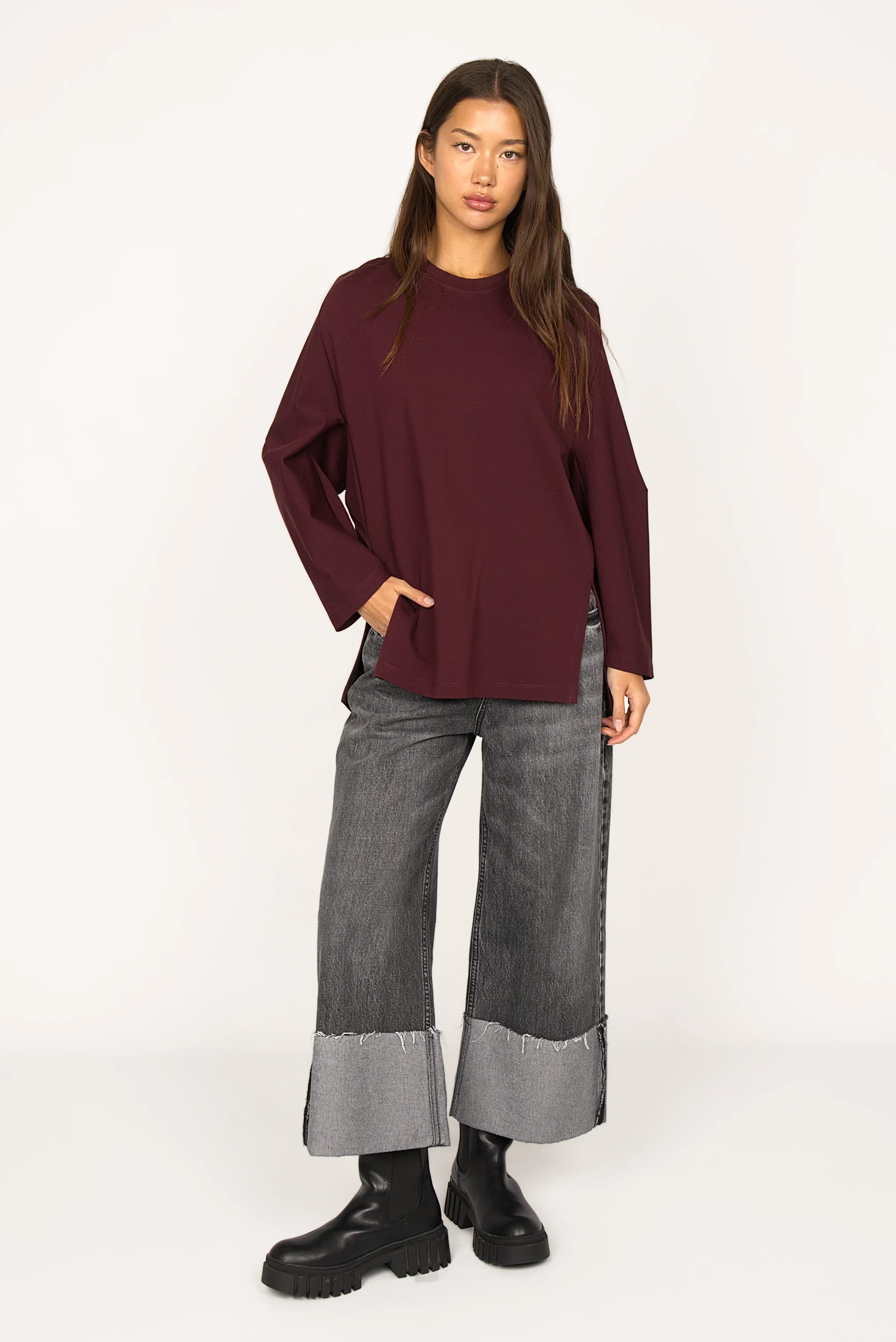 Frau trägt locker geschnittenes TOOVE Shirt aus elastischem Interlock-Jersey mit Rundhalsausschnitt und hohen Seitenschlitzen