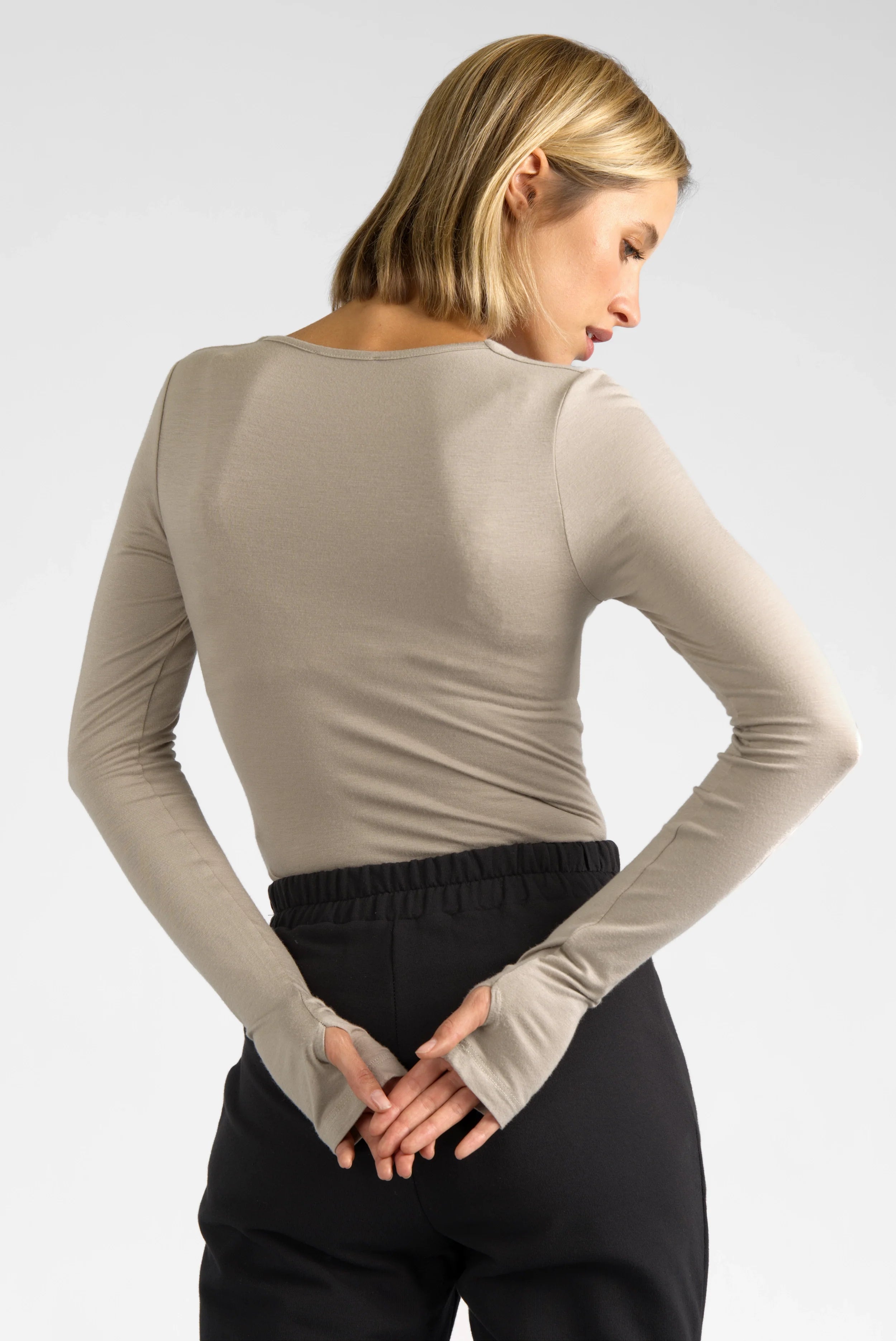 Damen trägt figurbetontes VALUM Longsleeve aus weicher Viskose mit U-Boot Ausschnitt und Daumenlöchern in Beige