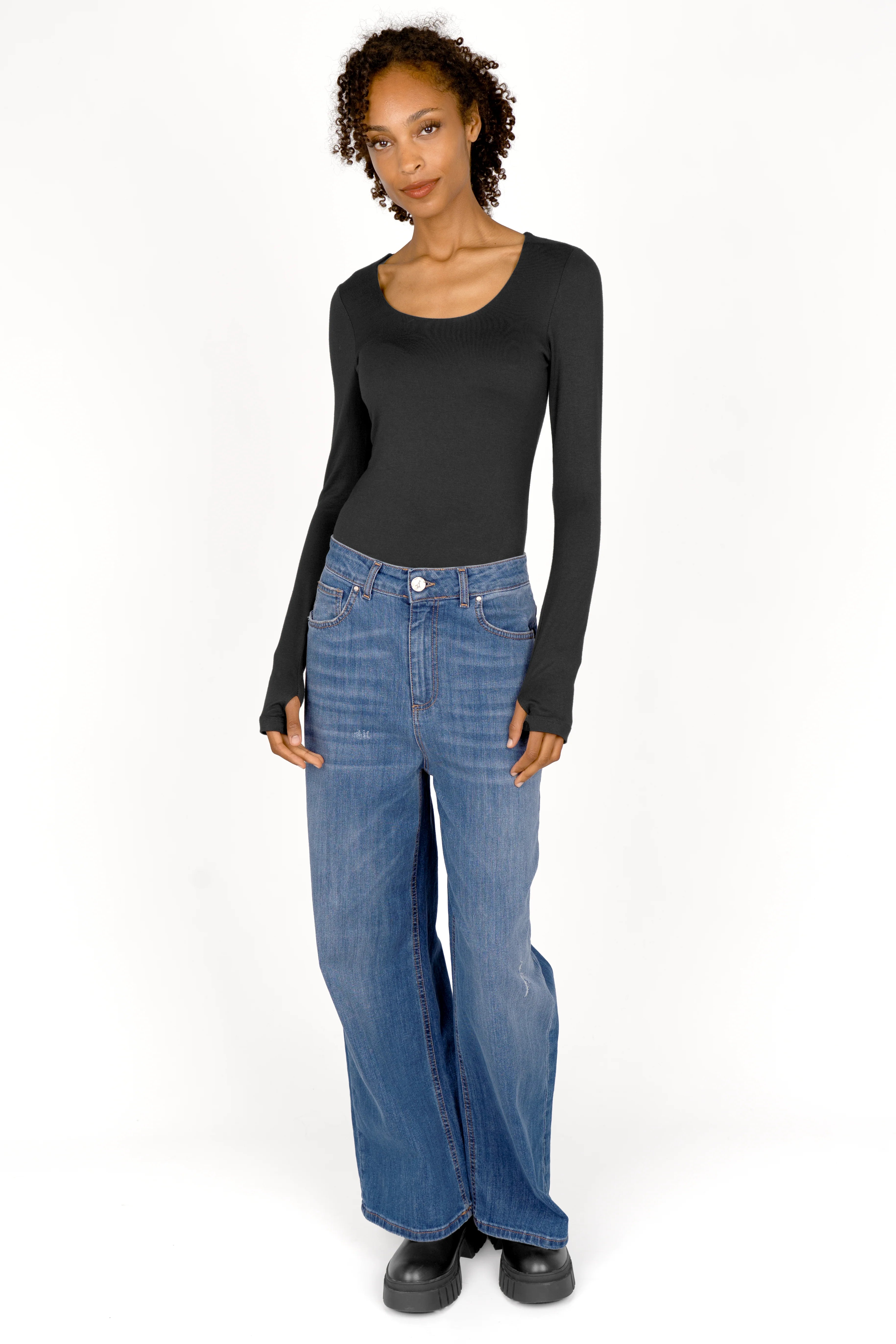 Woman wearing black VALUM Longsleeve with thumb holes and blue wide-leg jeans