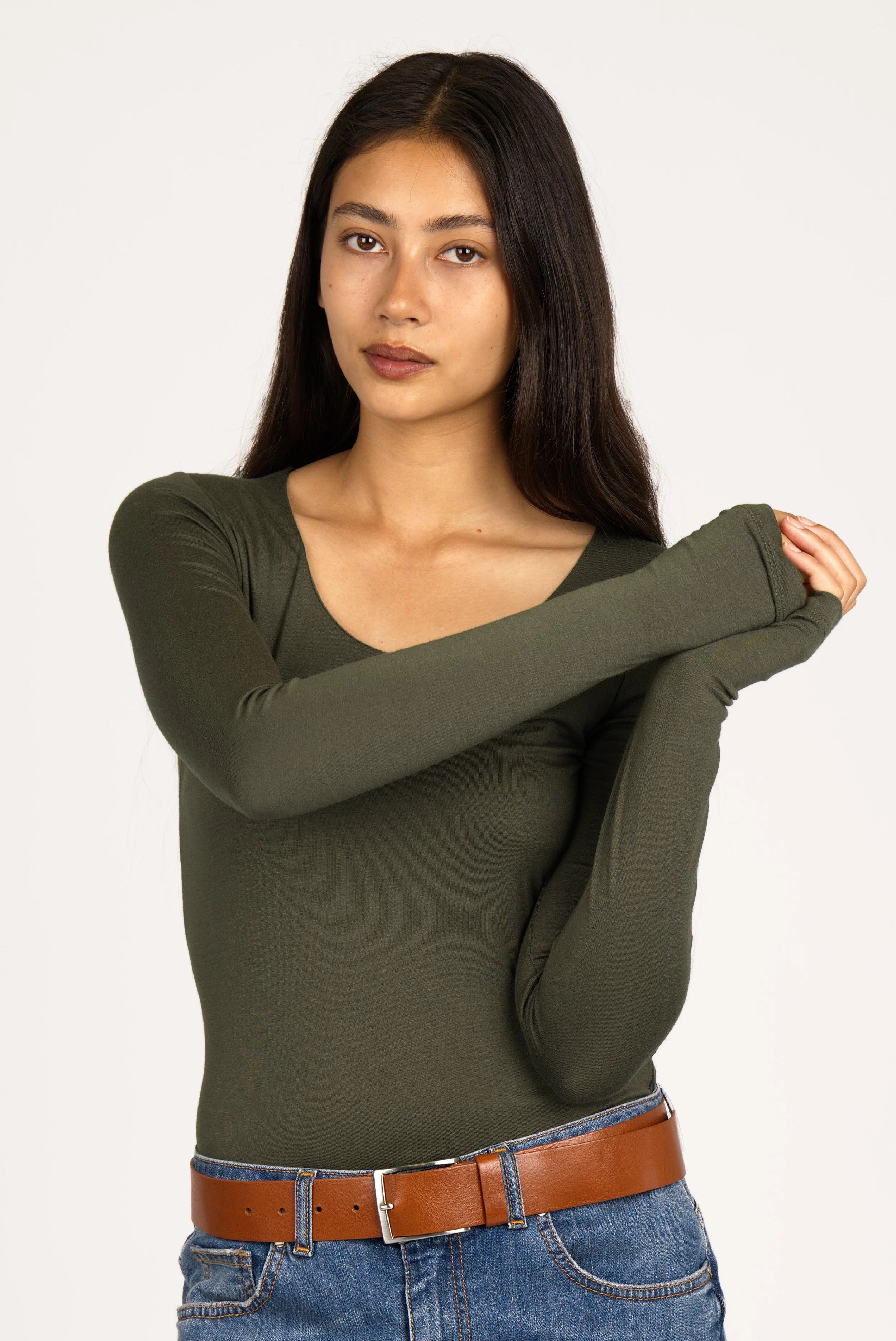 Woman wearing olive green VALUM Longsleeve with U-boat neckline, extra long sleeves, and thumb holes.