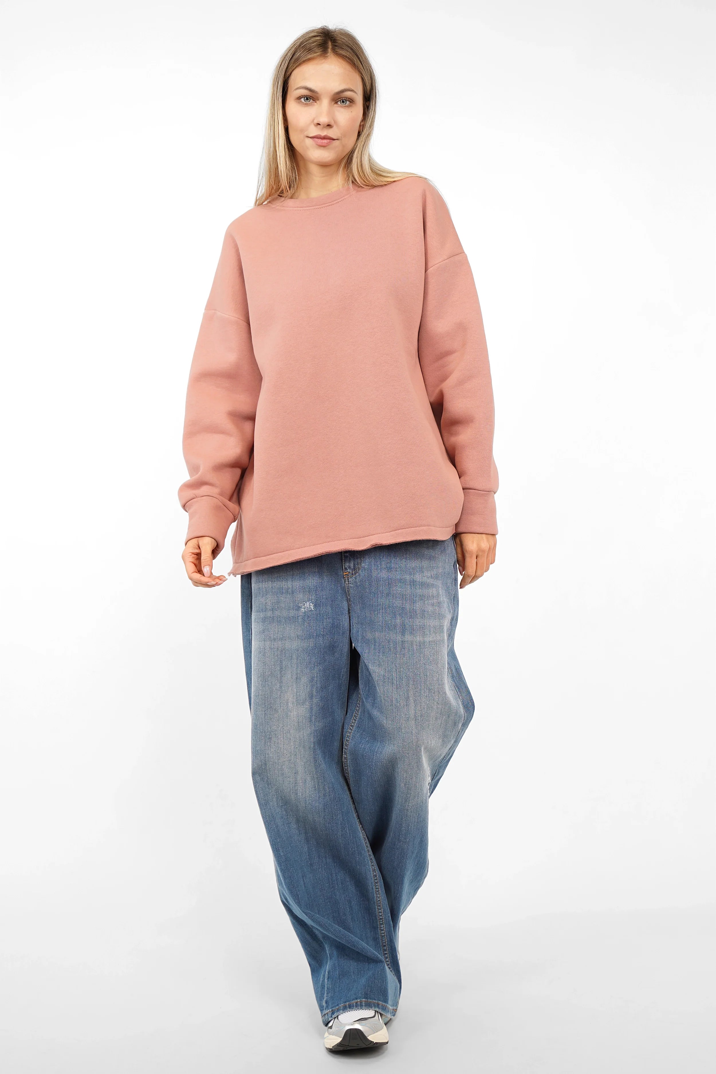 Frau trägt VIOLE Cozy Sweater aus weicher Baumwolle mit A-Linie, Rundhalsausschnitt und offenen Details, kombiniert mit blauer Jeans