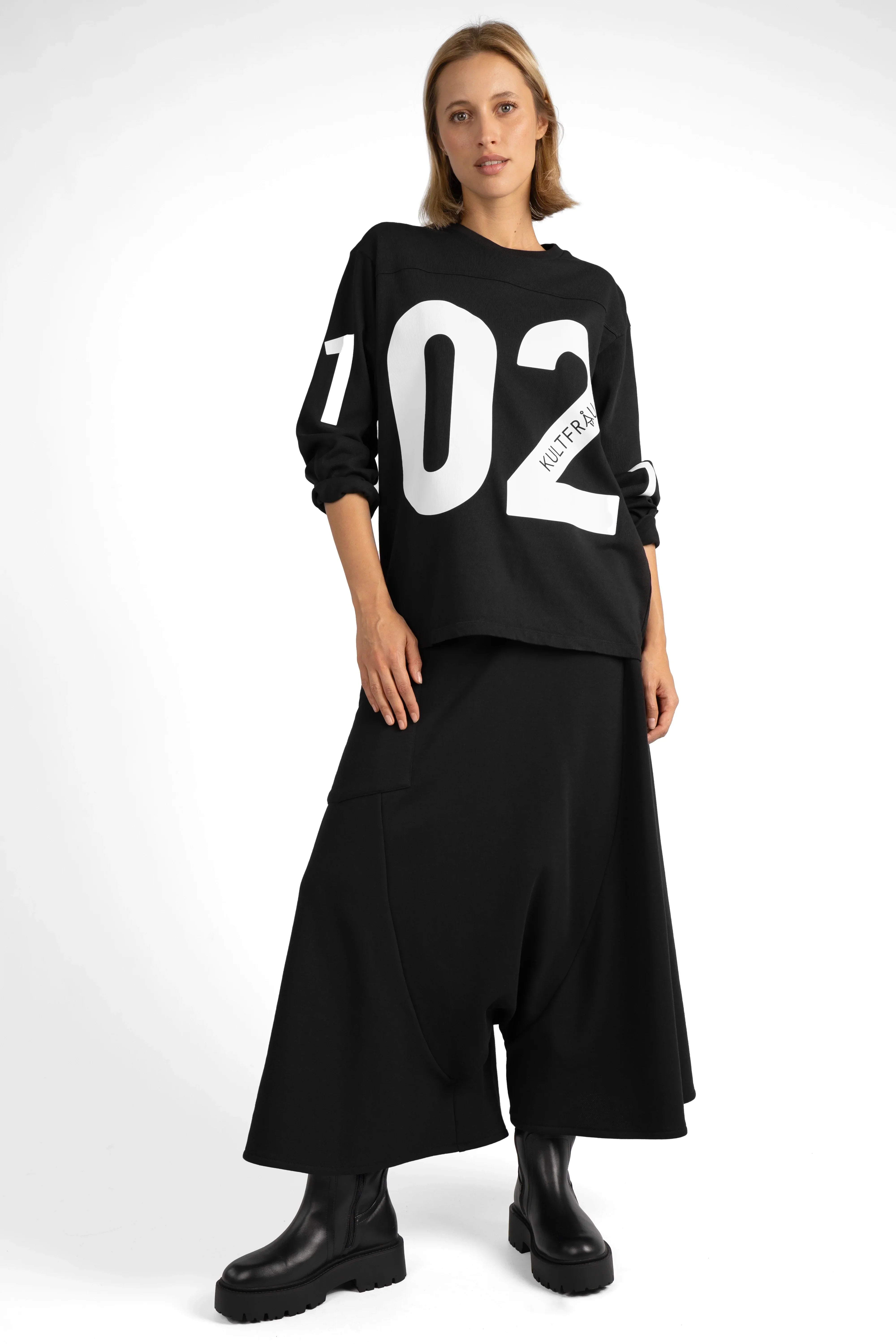 Frau trägt radikal weiten VISLA Hosenrock aus schwarzem Sweat mit asymmetrischer Tasche und Teilungsnähten