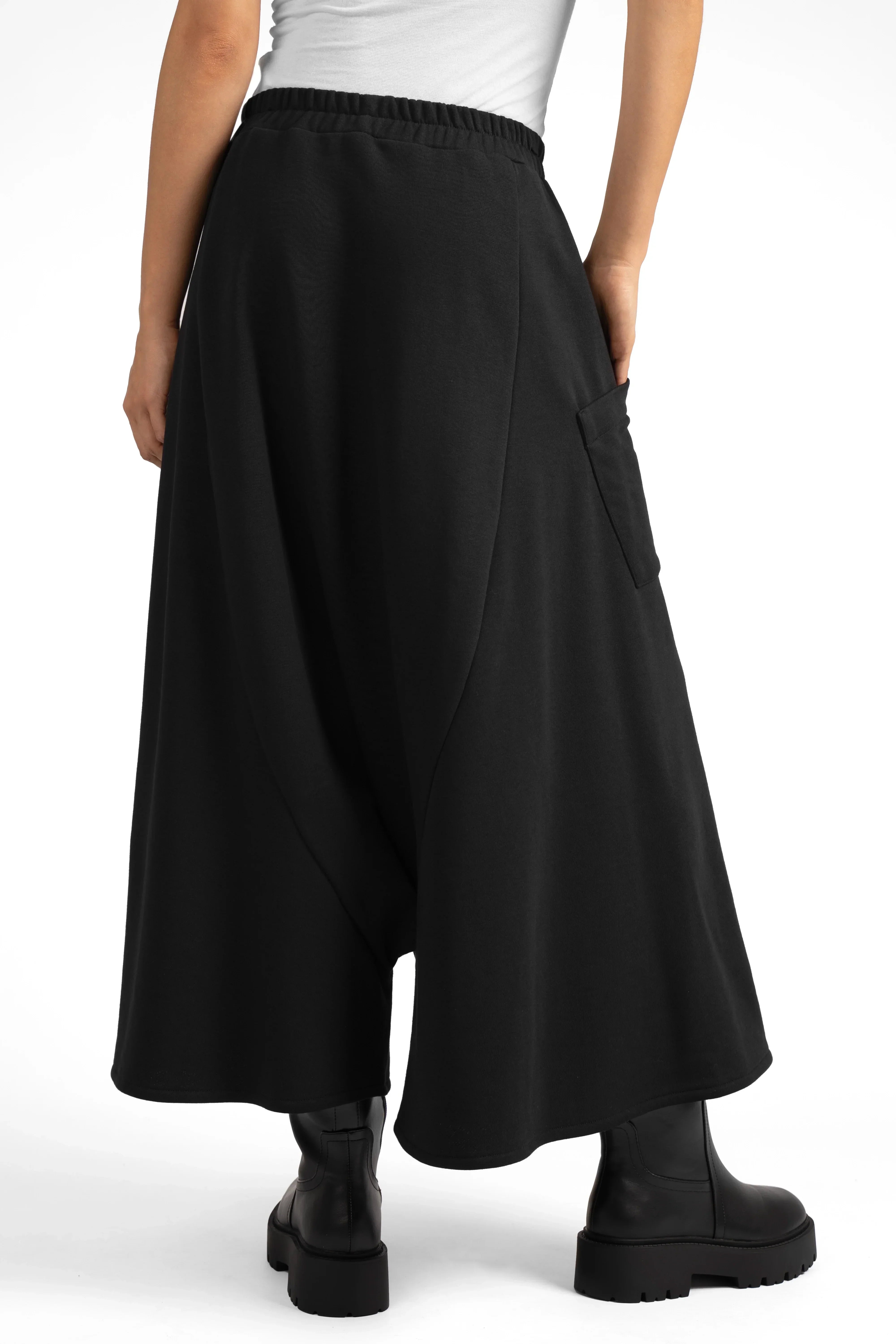 Frau trägt schwarzen VISLA Hosenrock aus Sweat mit weitem Schnitt und asymmetrischer Tasche hinten.