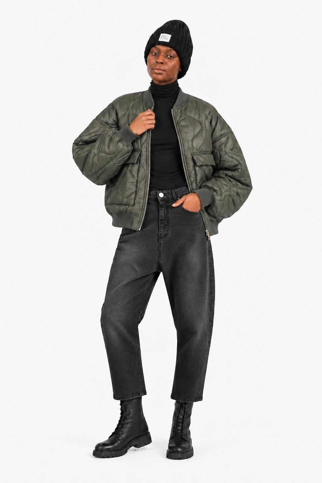 LARNA Bomberjacke in Green Frost, offen getragen mit JEANY Baggy Jeans in Faded Black, schwarzem Rollkragen, Mütze und Boots.