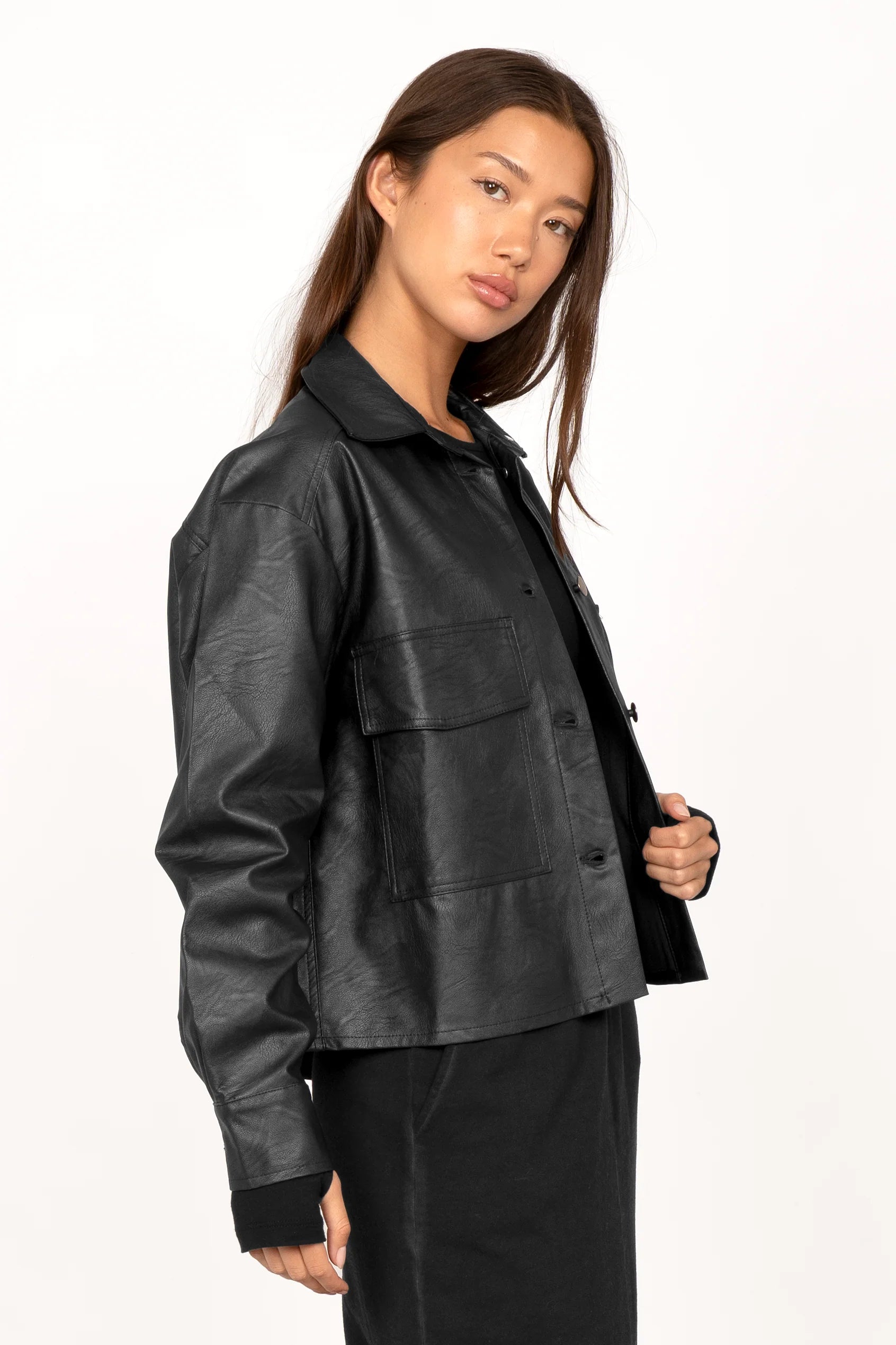 Black cropped SOOAE hem shirt jacket made of supersoft eco-leather with Kent collar and chest pockets worn by a woman