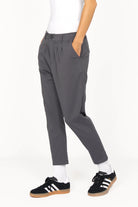 Dunkelgraue HEELENA OG Tapered Pants mit cropped Länge und schmal zulaufendem Bein, kombiniert mit Sneakern.