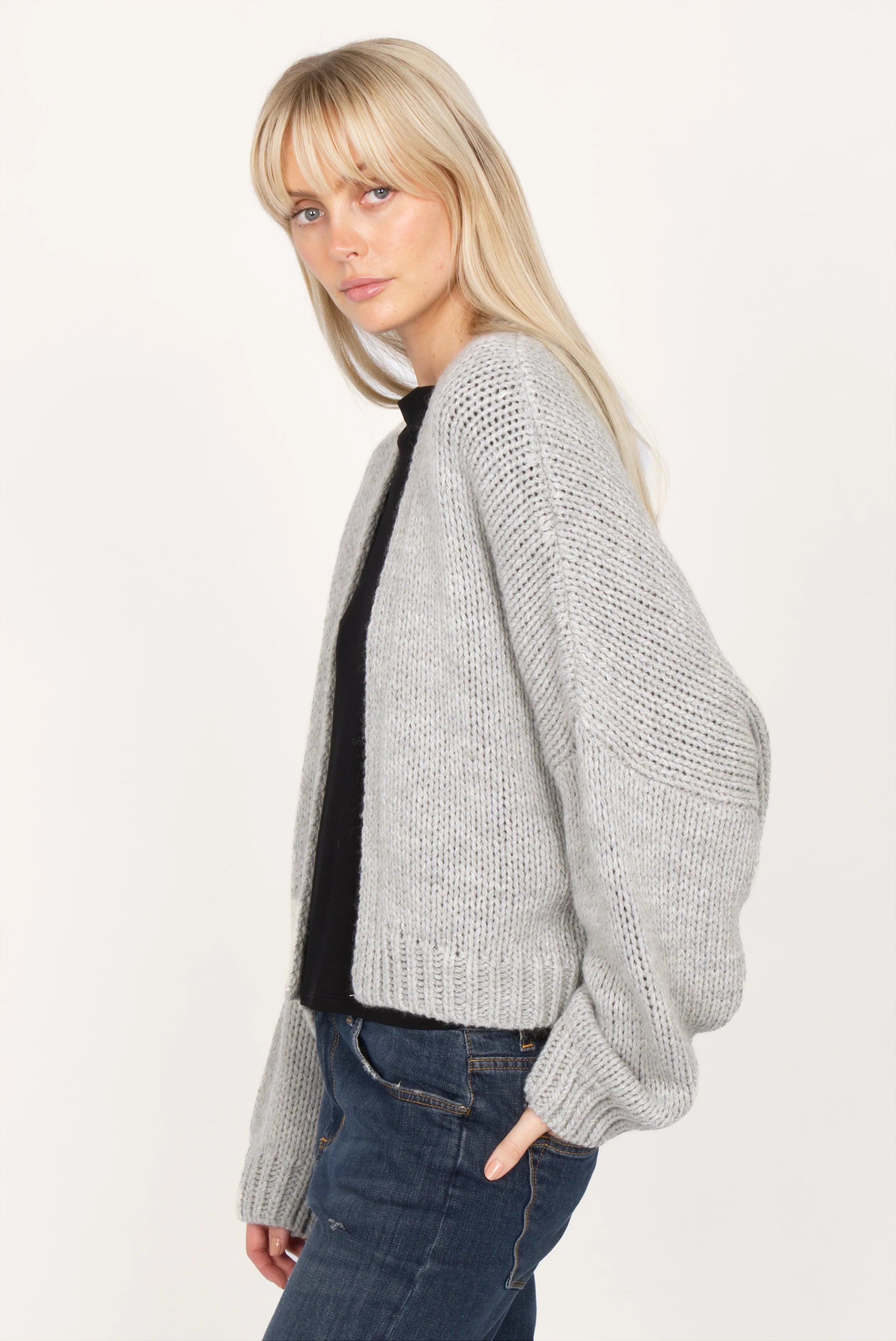 Woman wearing ALIXA Cropped Strickcardigan in light gray with loose fit and ribbed cuffs.