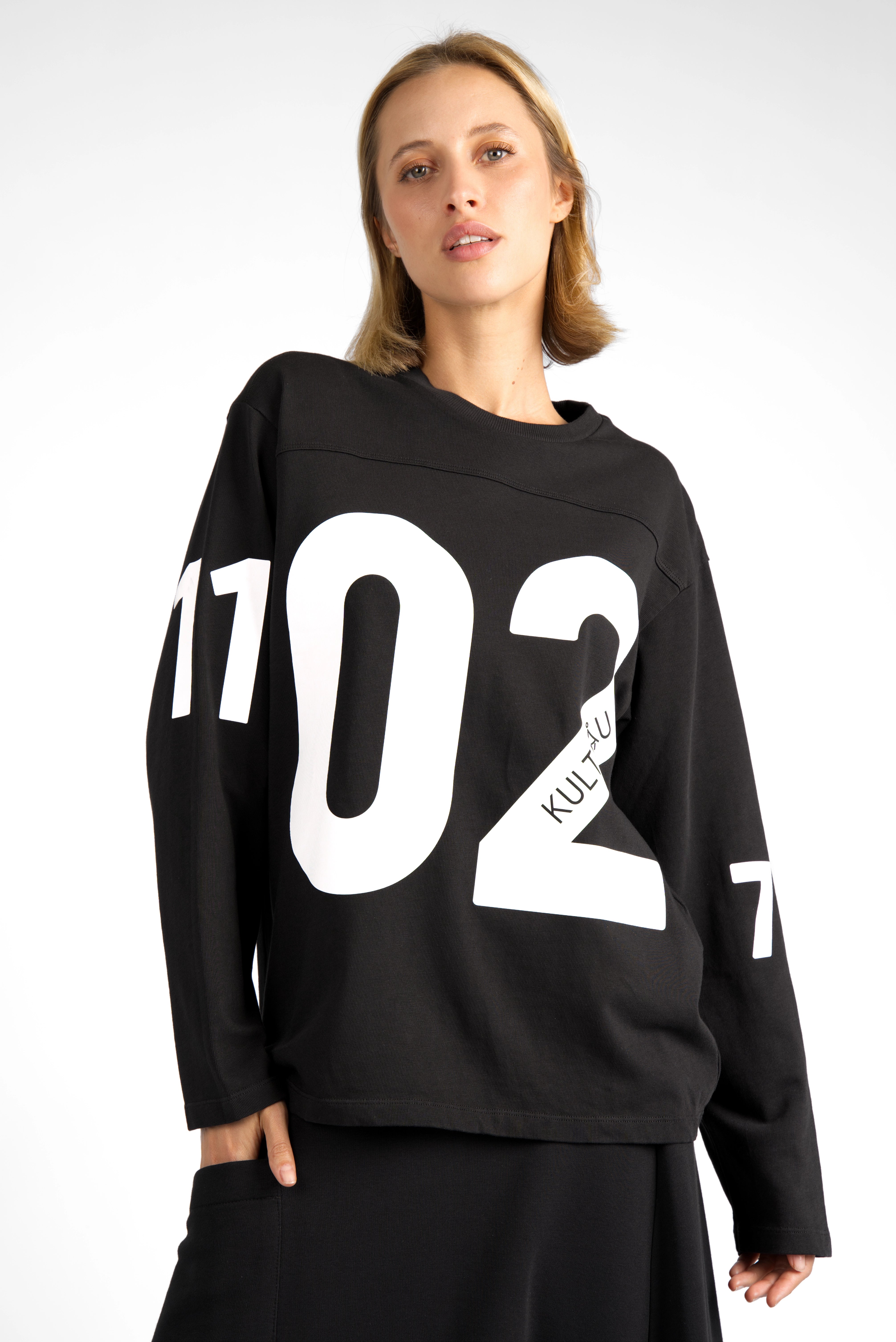 Black AGA Statement Sweater with bold white number prints on chest and sleeves, round neckline, regular fit, worn by female model