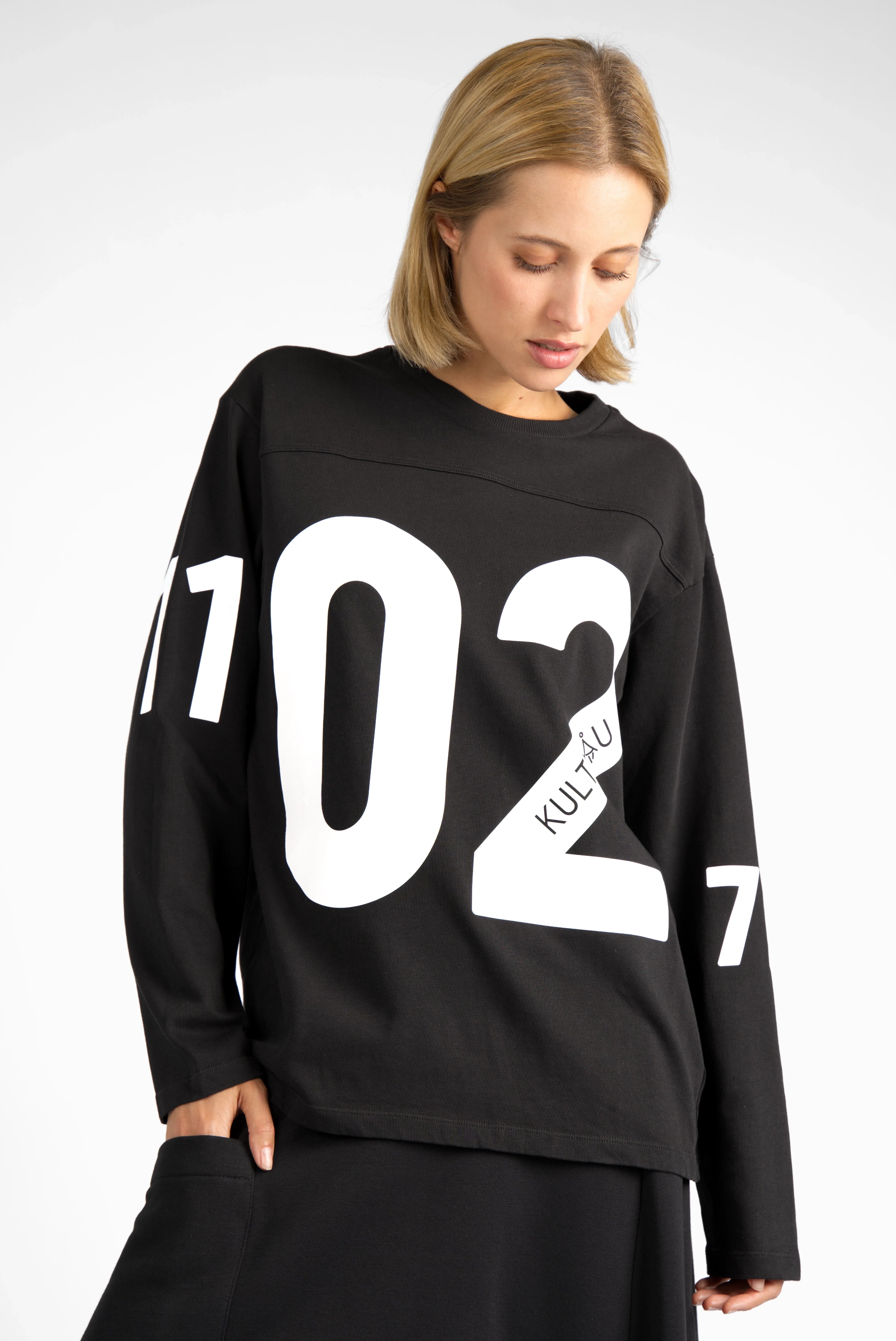 Black AGA Statement Sweater with bold white number prints on front and sleeves, oversized fit, and round neckline.