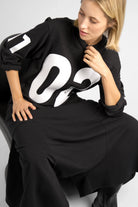 Black AGA Statement Sweater with large white number prints on chest and sleeves, worn by model.