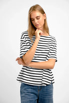 Woman wearing AILIE T-Shirt with black and white stripes, minimalist boat neckline, and regular fit.