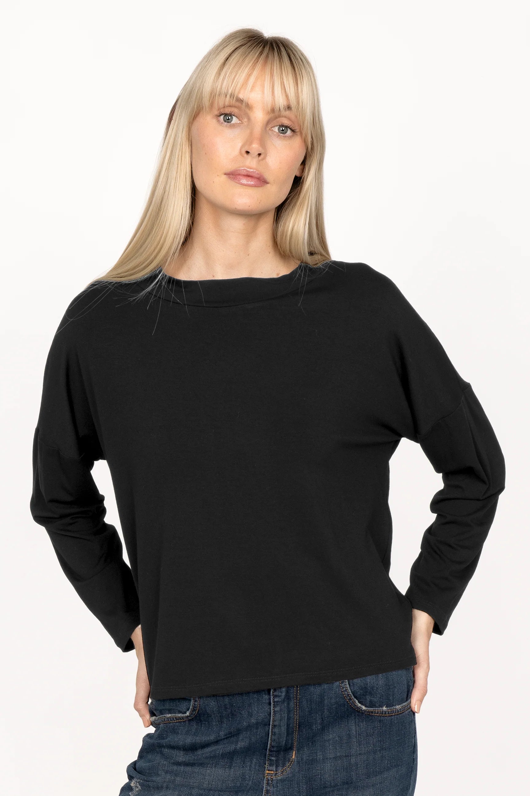 Woman wearing black longsleeve made of lightweight viscose jersey with loose neckline and dropped shoulders.
