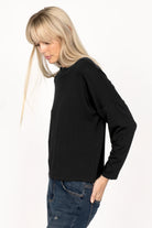 Woman wearing black longsleeve made of lightweight viscose jersey with relaxed neckline and dropped shoulders