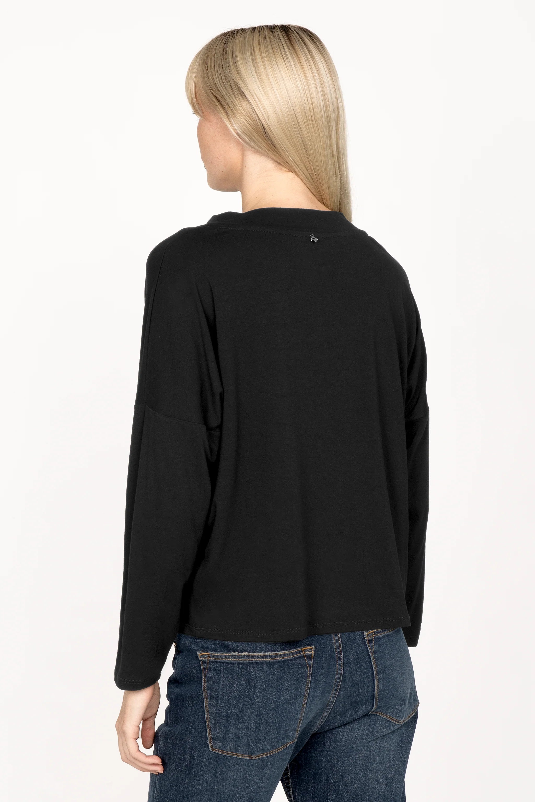 Woman wearing black longsleeve made of lightweight viscose jersey with loose neckline and dropped shoulders viewed from back