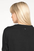 Back view of woman wearing black longsleeve made of lightweight viscose jersey with relaxed neckline and dropped shoulders