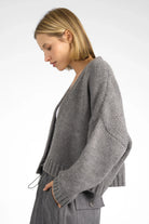 Woman wearing grey ALIXA Cropped Strickcardigan with loose fit and ribbed cuffs.