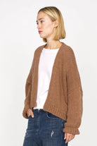 Woman wearing brown ALIXA Cropped Strickcardigan with loose fit and ribbed cuffs over white shirt and blue jeans