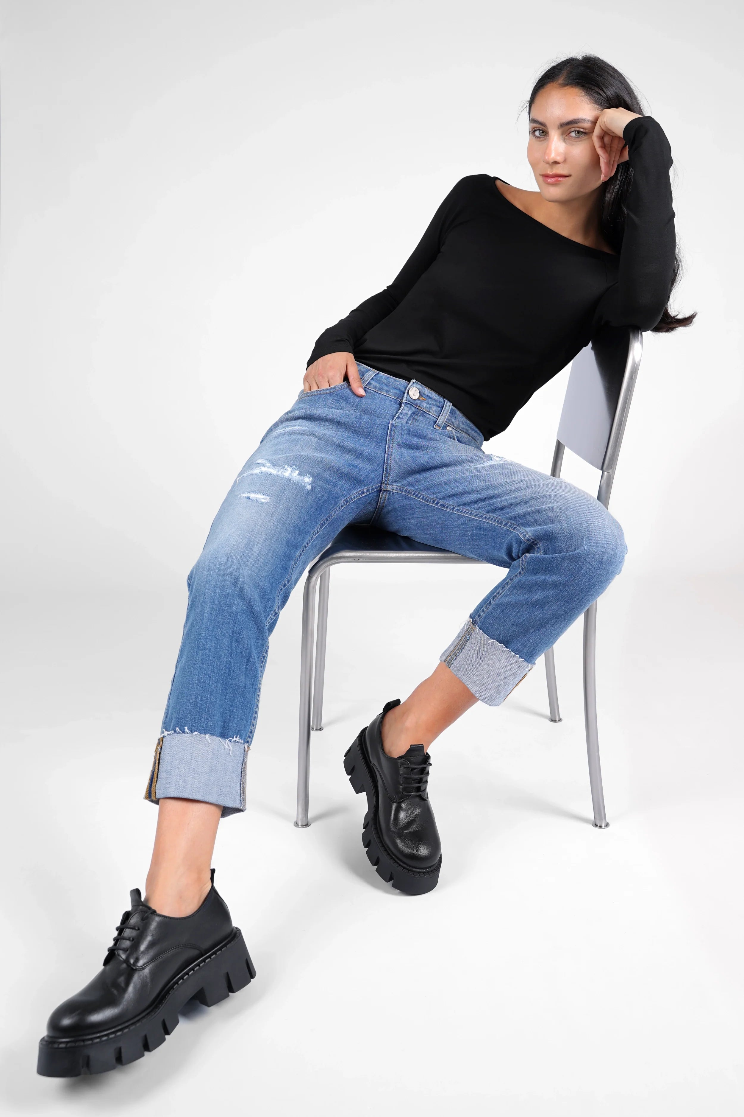 ALVA Boyfriend-Jeans in destroyed look with raw-cut cuff, mid waist, and relaxed fit on model sitting on chair