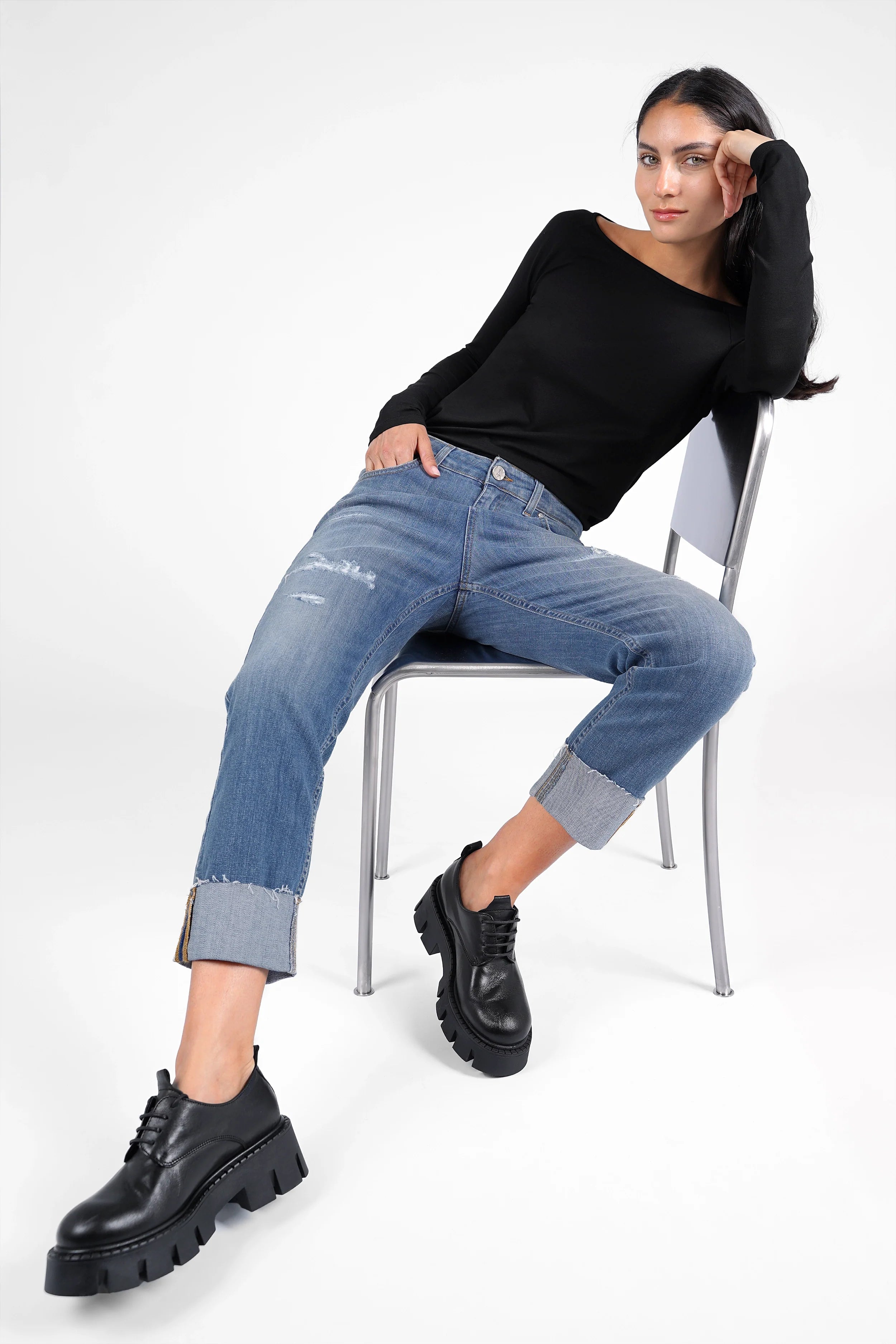 Damen trägt ALVA Boyfriend-Jeans mit Umschlag in Destroyed-Optik und schwarzen Chunky Boots, entspannter Sitz mit Raw-Cut Saum