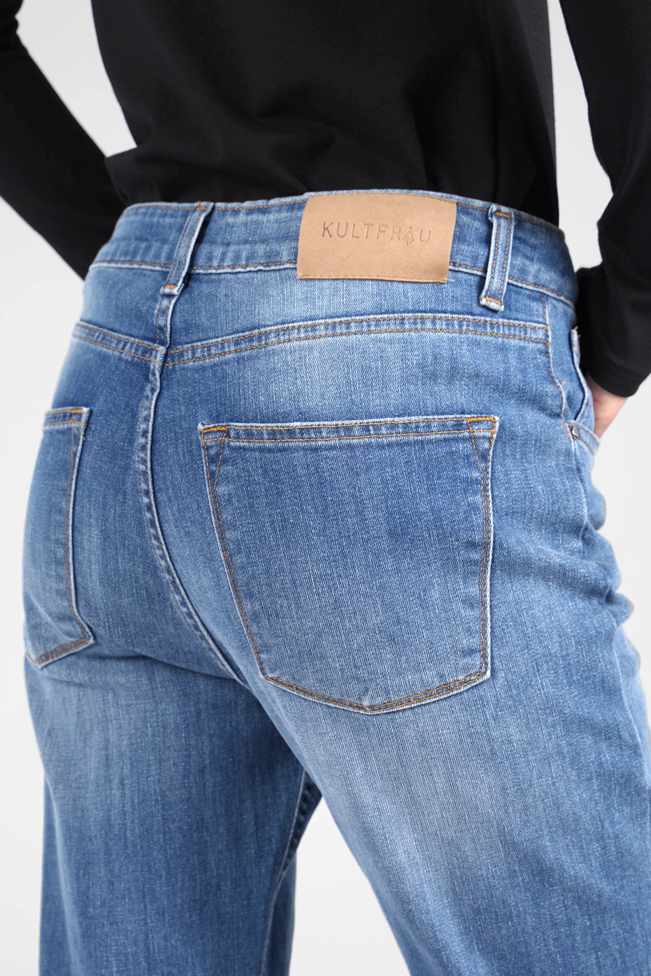 Close-up of ALVA Boyfriend-Jeans in mid-wash blue with raw-cut rolled cuffs and back pockets