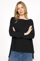 Woman wearing black AMALEA Relaxed Fit longsleeve with boat neckline, dropped shoulders, side slits, and extended back hem
