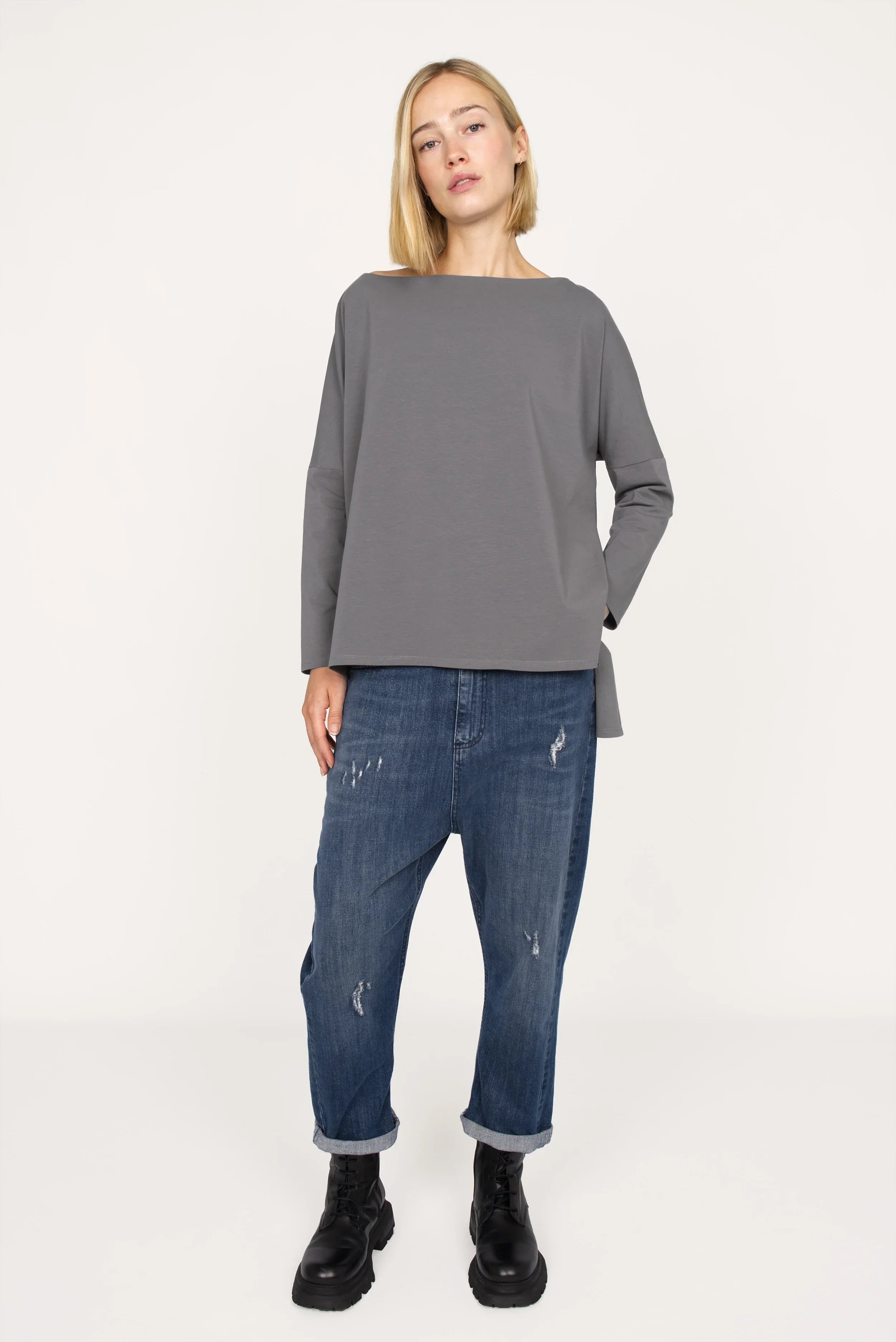 Woman wearing AMALEA Relaxed Fit grey longsleeve with boat neckline and relaxed fit paired with rolled-up blue jeans and black boots