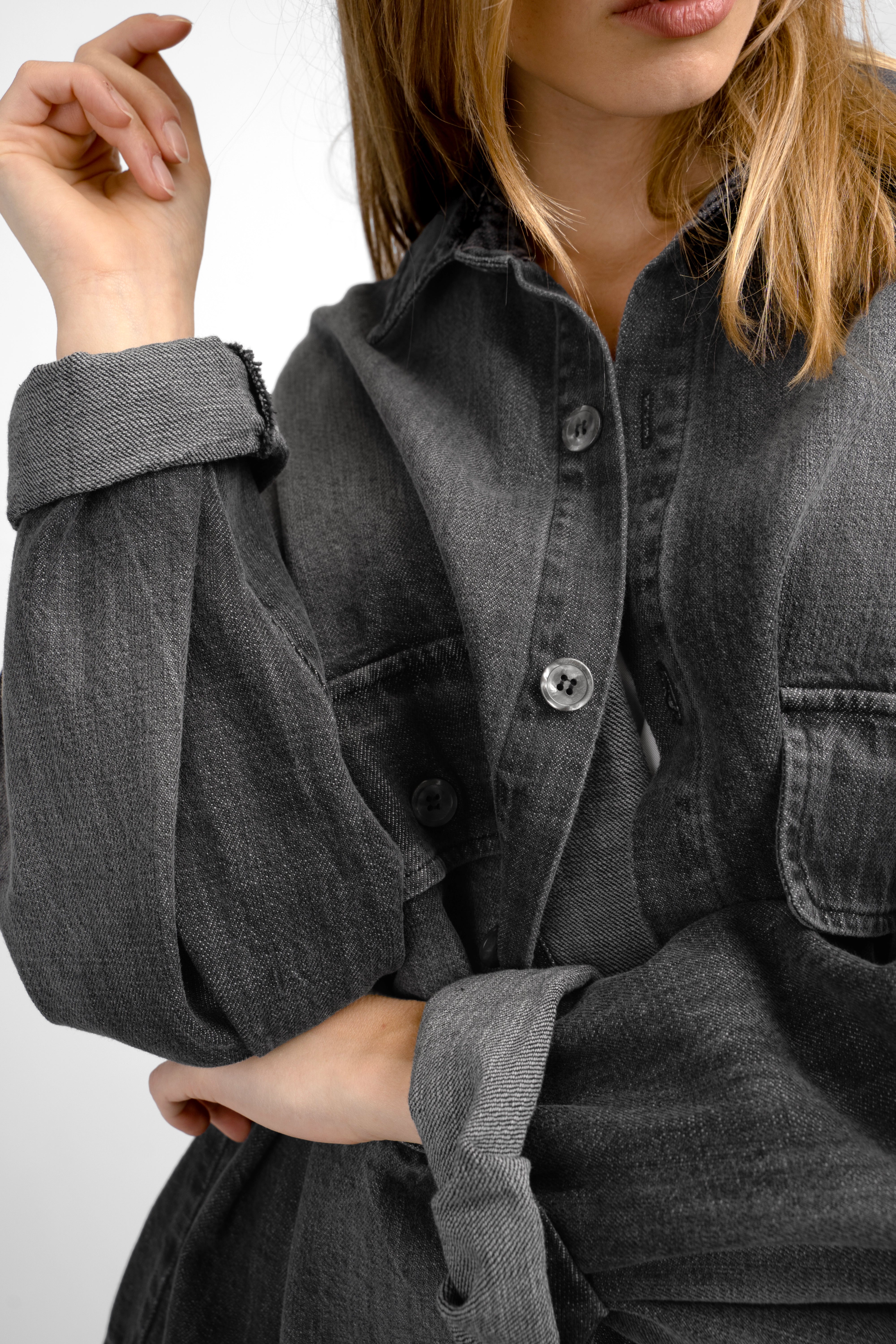 Close-up of a model wearing a dark gray ANEA oversized Hemdjacke with rolled-up sleeves and buttoned chest pockets.