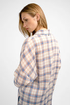 Woman wearing a relaxed fit ATLE Hemd with light crinkle texture and semi-transparent plaid fabric, featuring dropped shoulders and chest pockets.