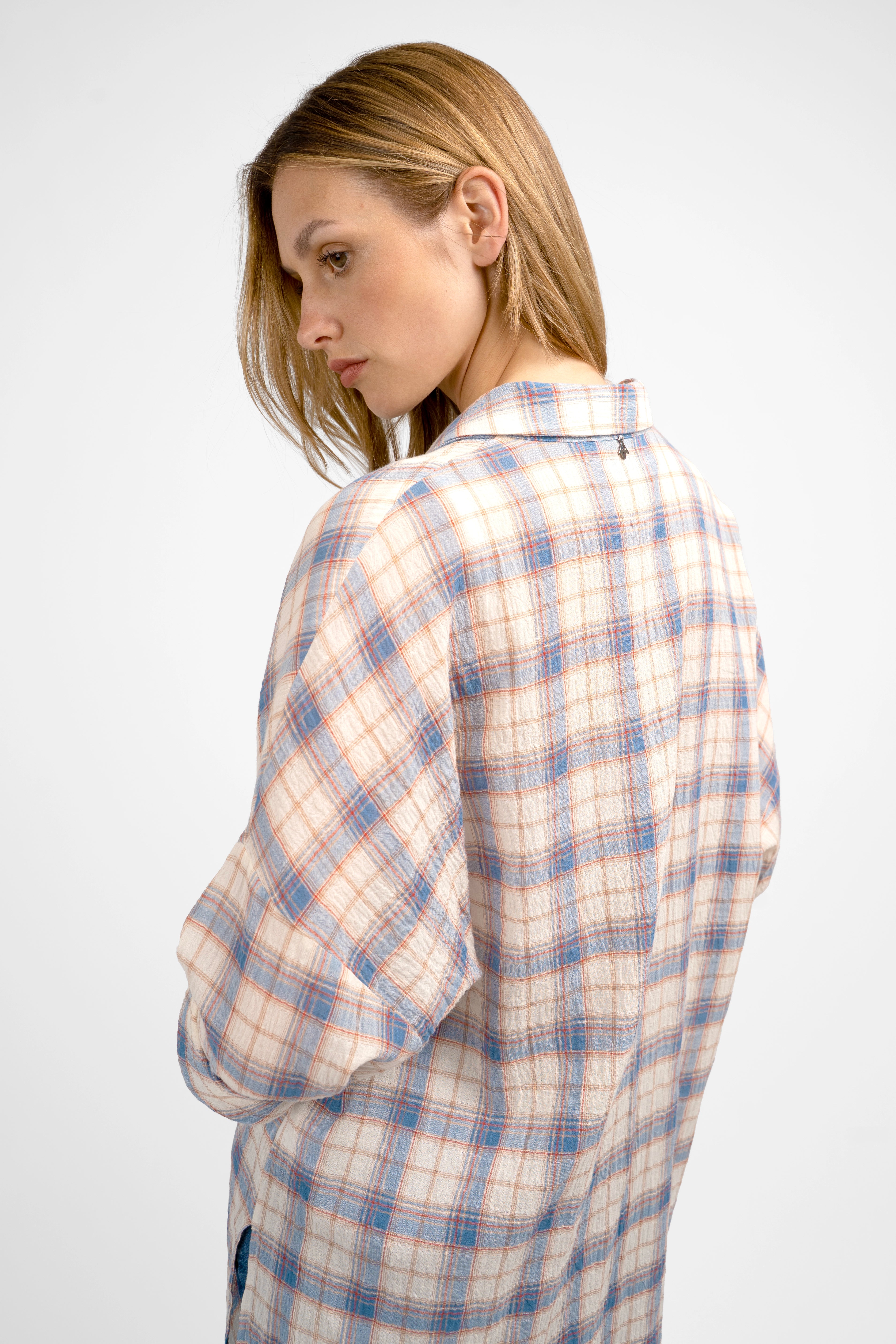 Woman wearing a relaxed fit ATLE Hemd with light crinkle texture and semi-transparent plaid fabric, featuring dropped shoulders and chest pockets.