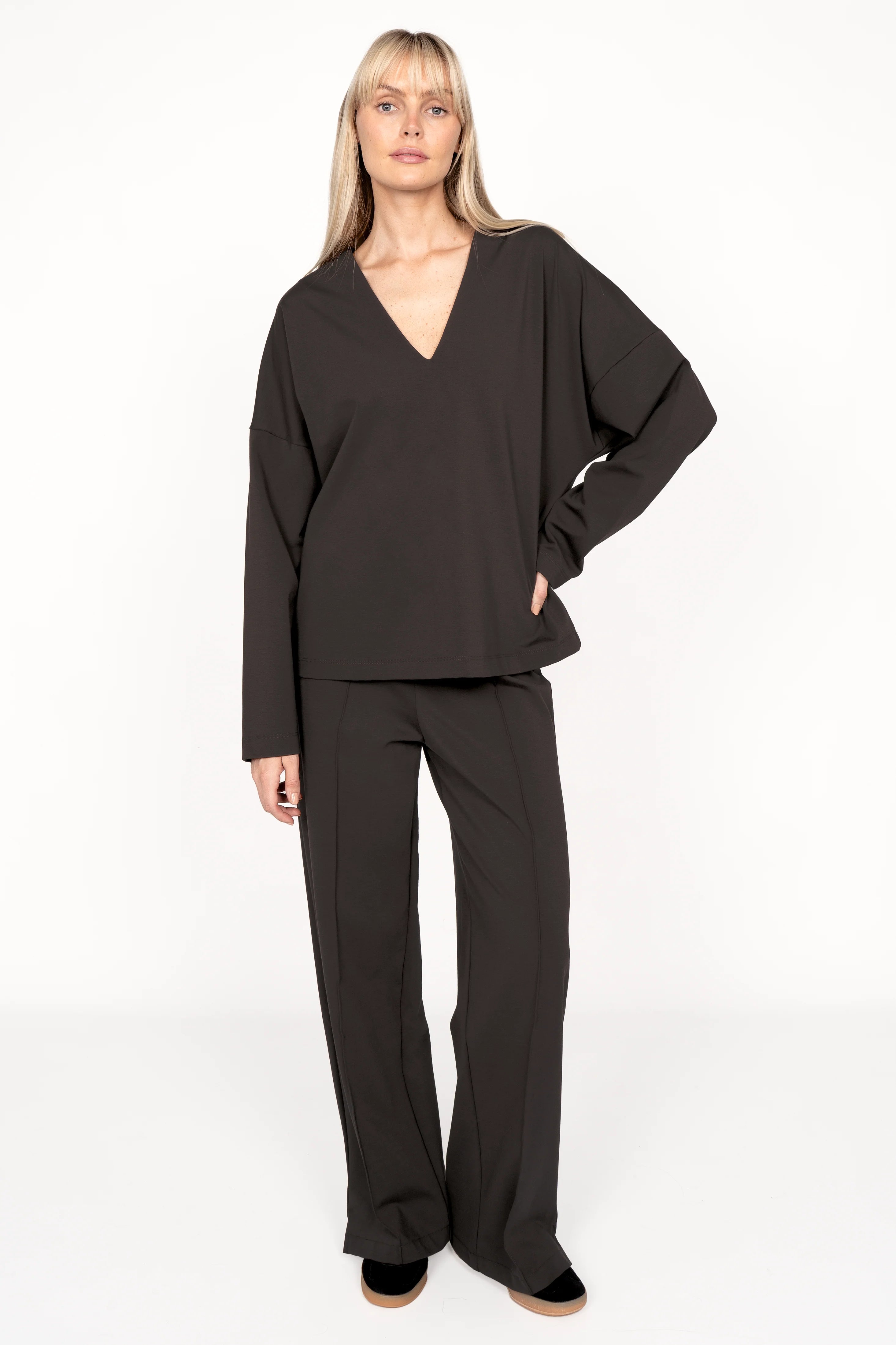 Woman wearing BERLEY Relaxed V-Neck Bluse in black compact jersey with relaxed fit and subtle front pleat.