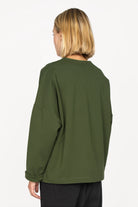 Back view of a person wearing a green BERLEY Relaxed V-Neck Bluse with relaxed fit, dropped shoulders, and long straight sleeves.