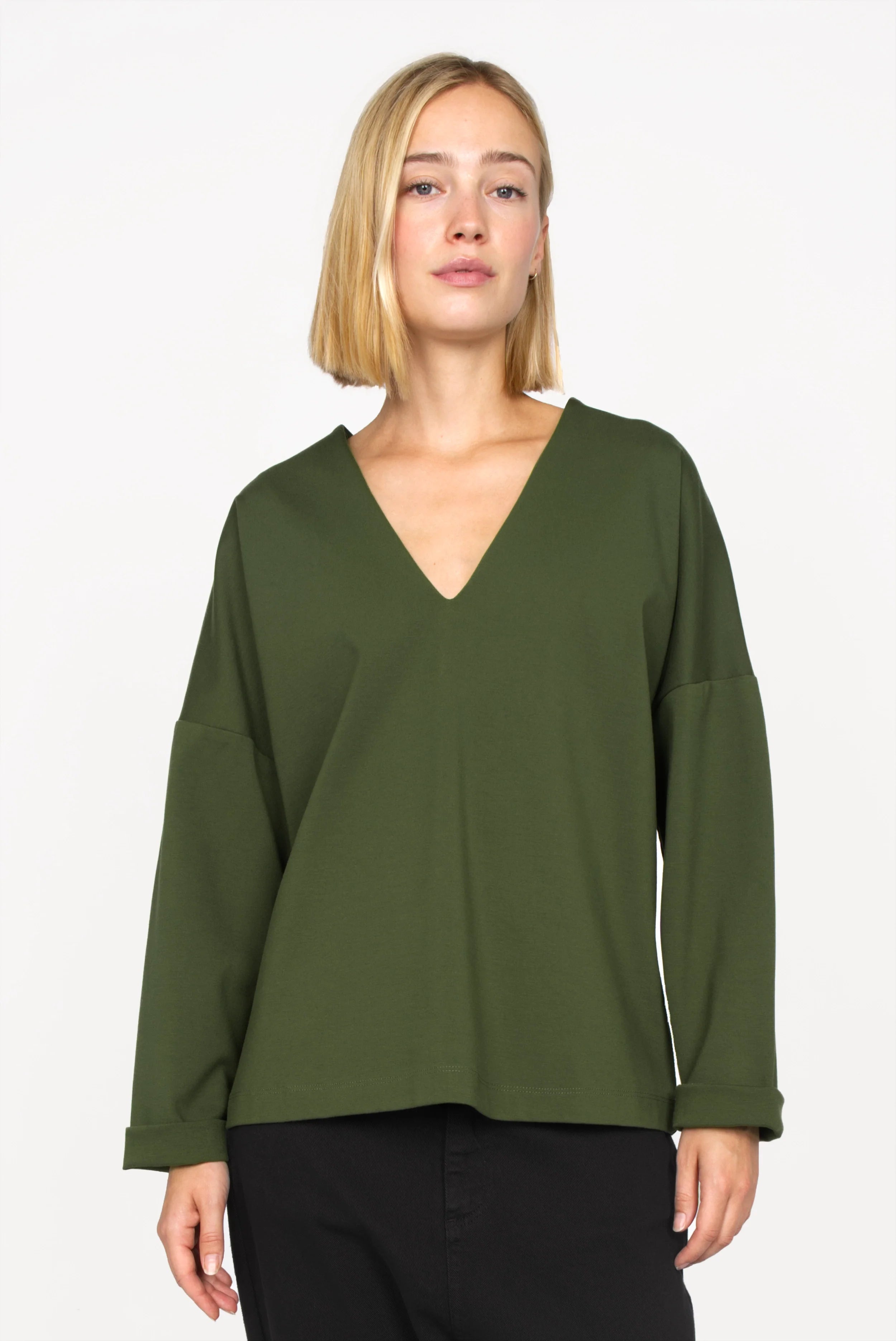 Woman wearing olive green BERLEY Relaxed V-Neck Bluse with dropped shoulders and straight long sleeves.