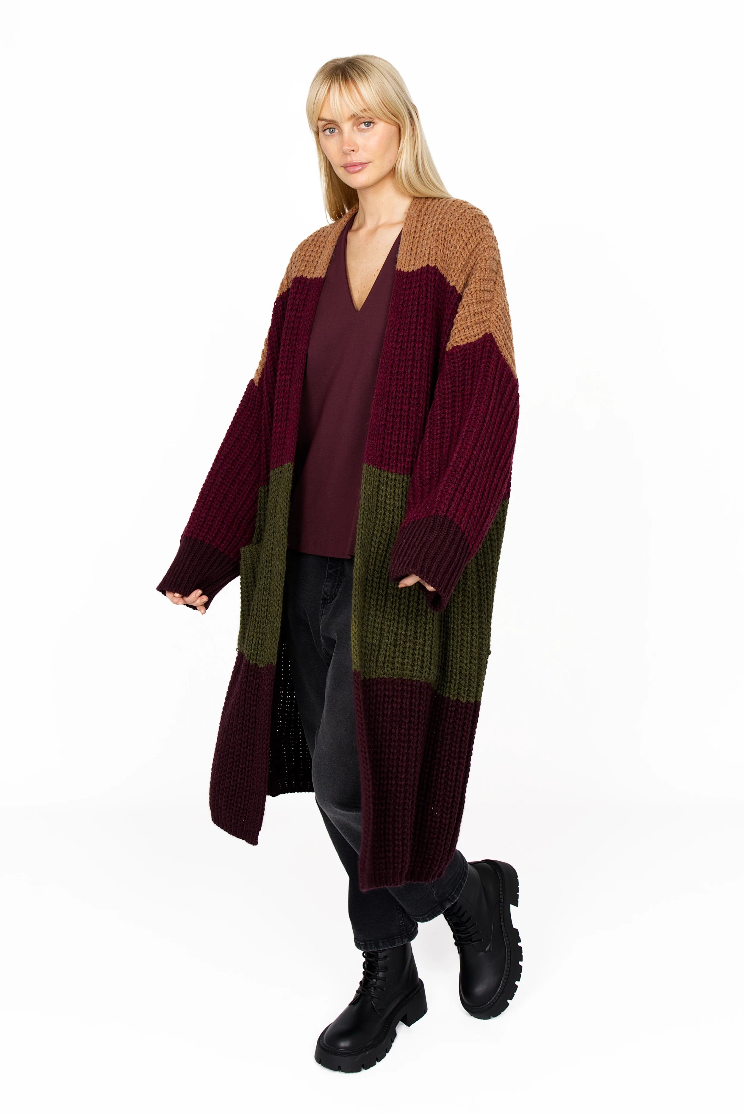 Woman wearing BERLEY Relaxed V-Neck Bluse in burgundy with a long color-block cardigan and black boots.
