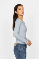 Slim fit BETTIE Longsleeve in light blue with ribbed fine knit, extra long sleeves, and round neckline worn by woman.
