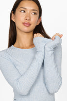 Woman wearing light blue BETTIE Longsleeve with slim fit, fine rib texture, and extra long sleeves.