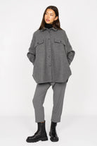 Woman wearing a gray BJORA Overshirt made of wool blend with chest pockets and side pockets, styled with gray pants and black boots.