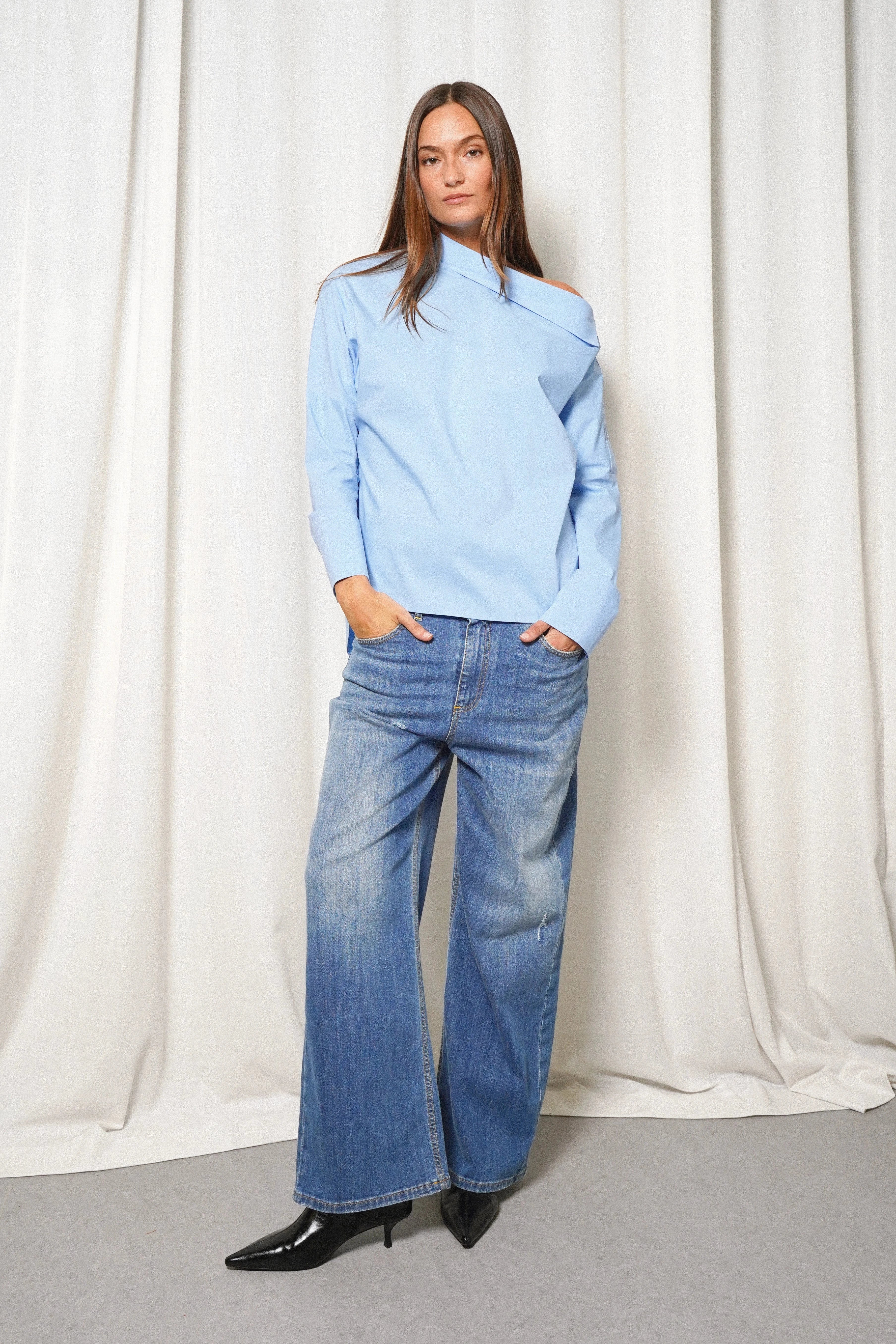 Damen trägt Boni asymmetrische Bluse mit One-Shoulder-Design und verlängerter Rückenpartie