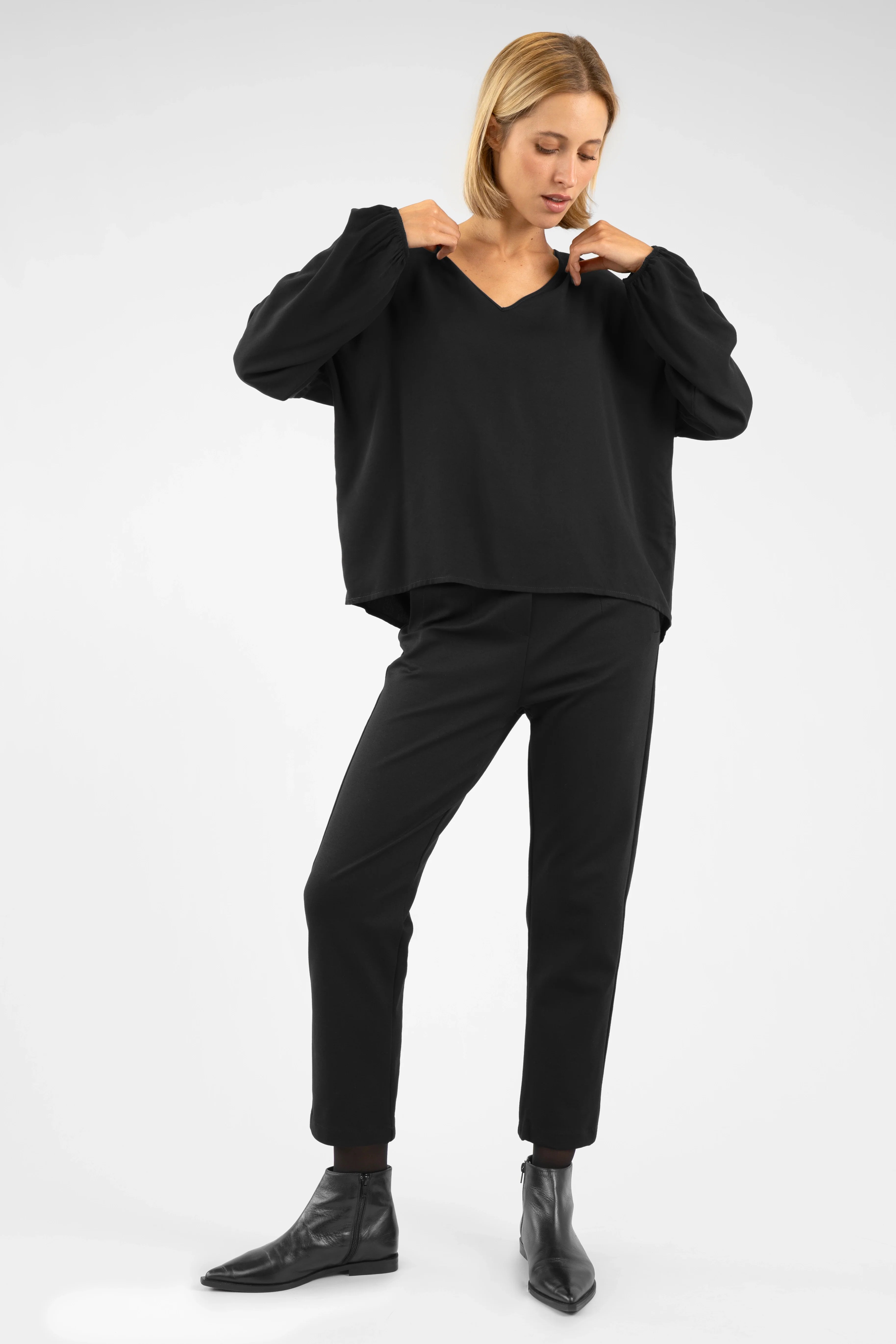 Woman wearing black CEELIA Zigarettenhose slim cropped pants with elastic waistband and decorative seams.