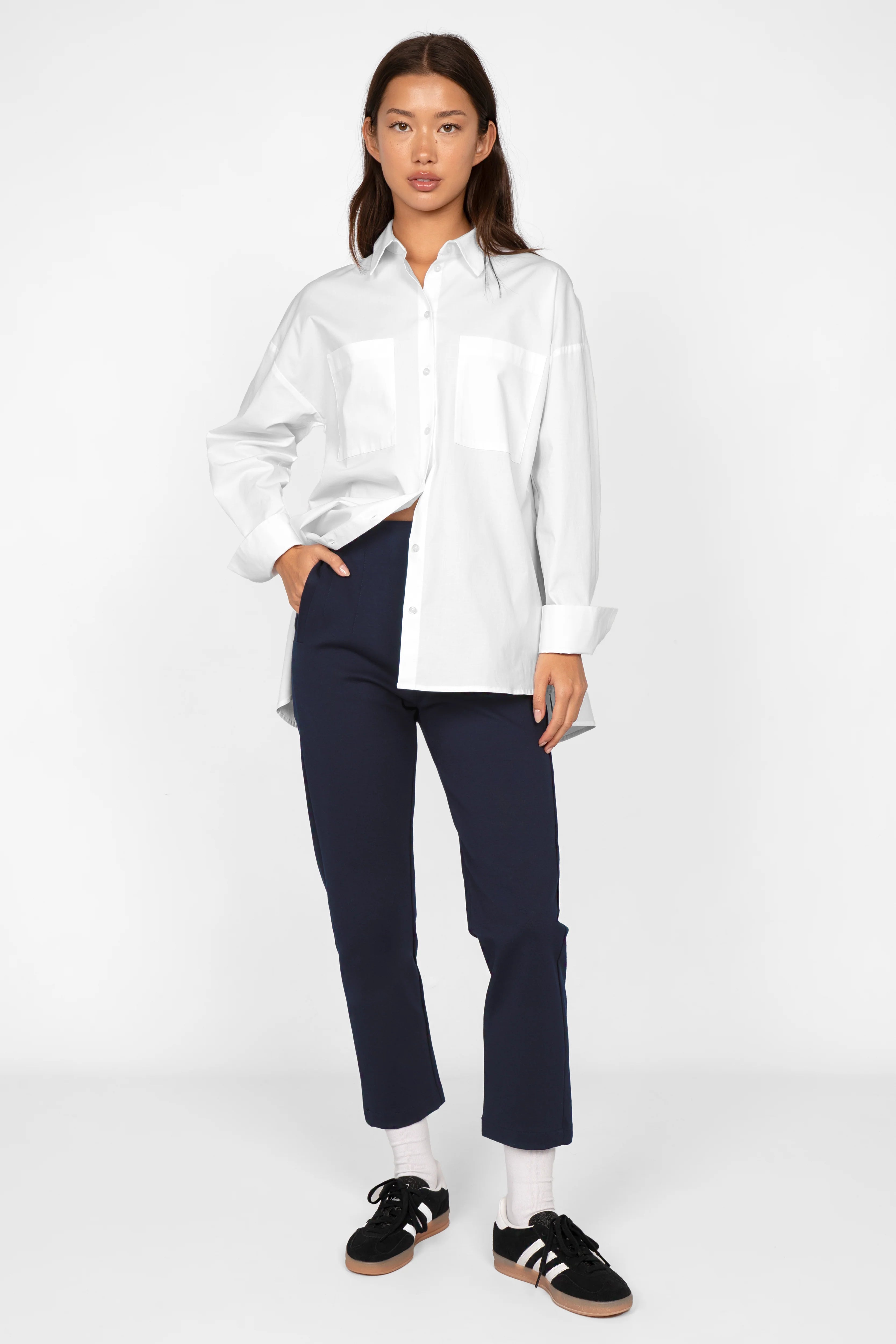 Slim fit CEELIA ankle pants in navy with high waist and elastic back waistband, paired with a white shirt and black sneakers.